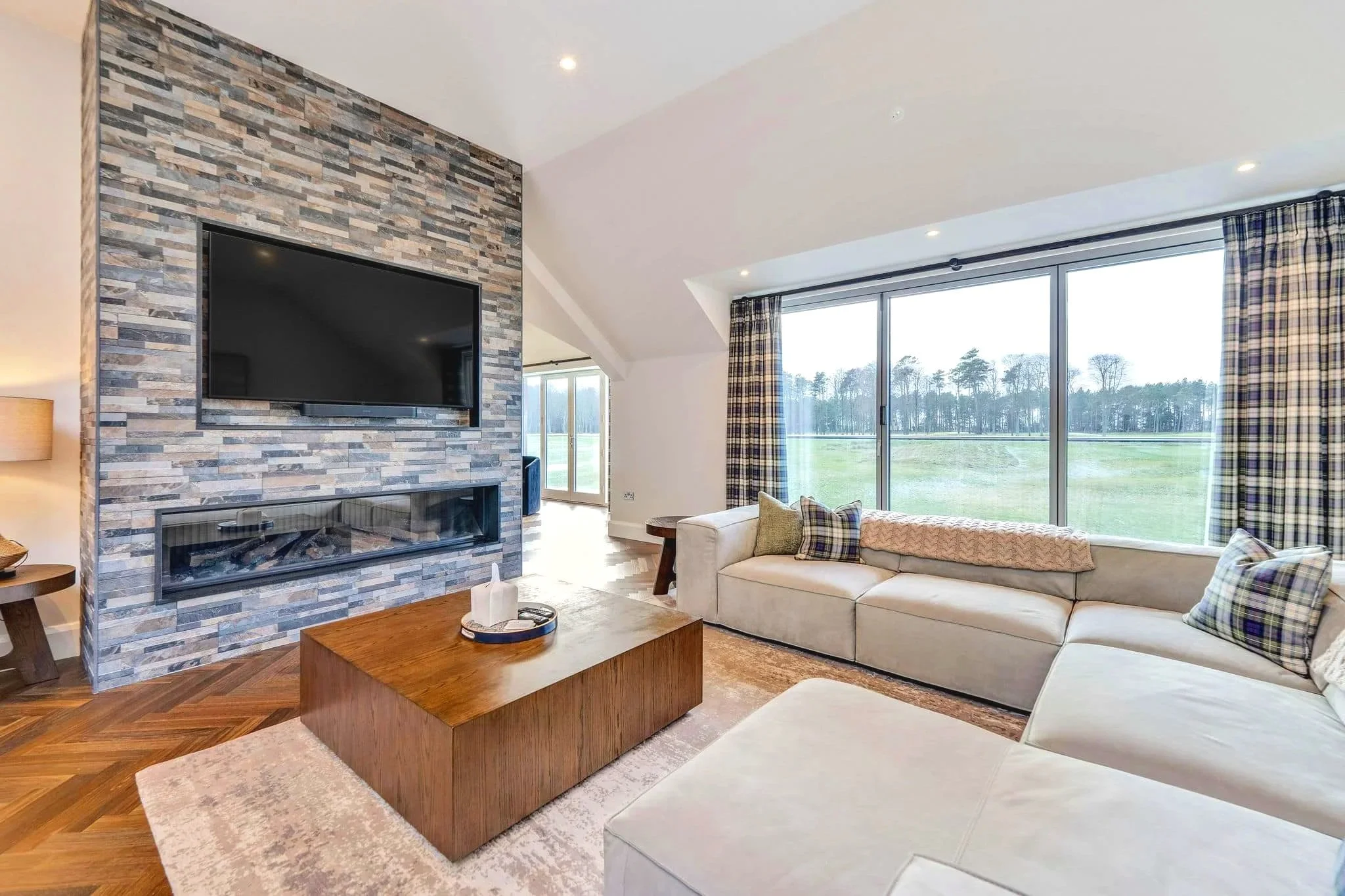 High-end living room with feature stone fireplace and large windows overlooking golf course.