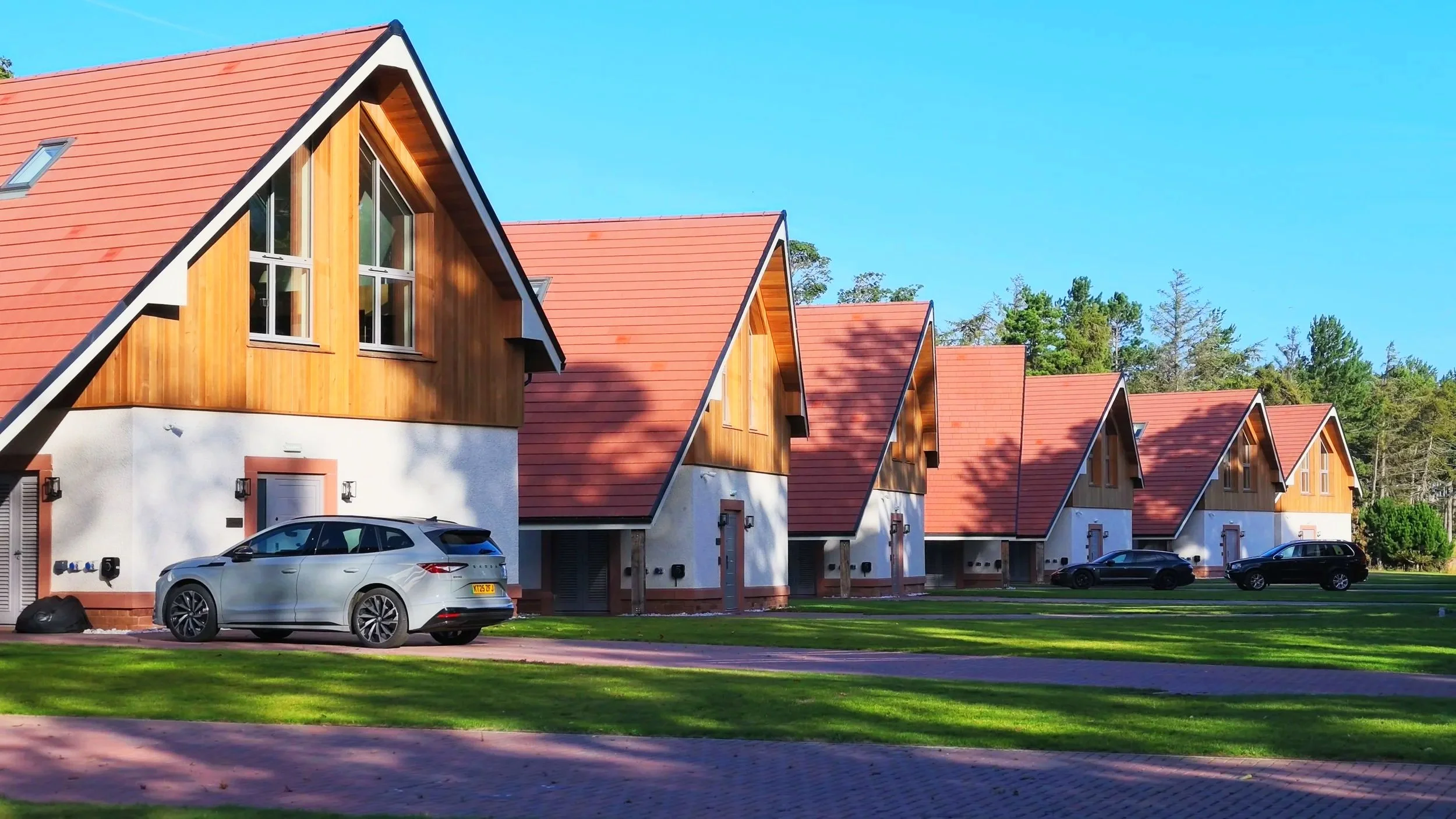 Contemporary timber-clad holiday cabin with pitched roof in landscaped setting.