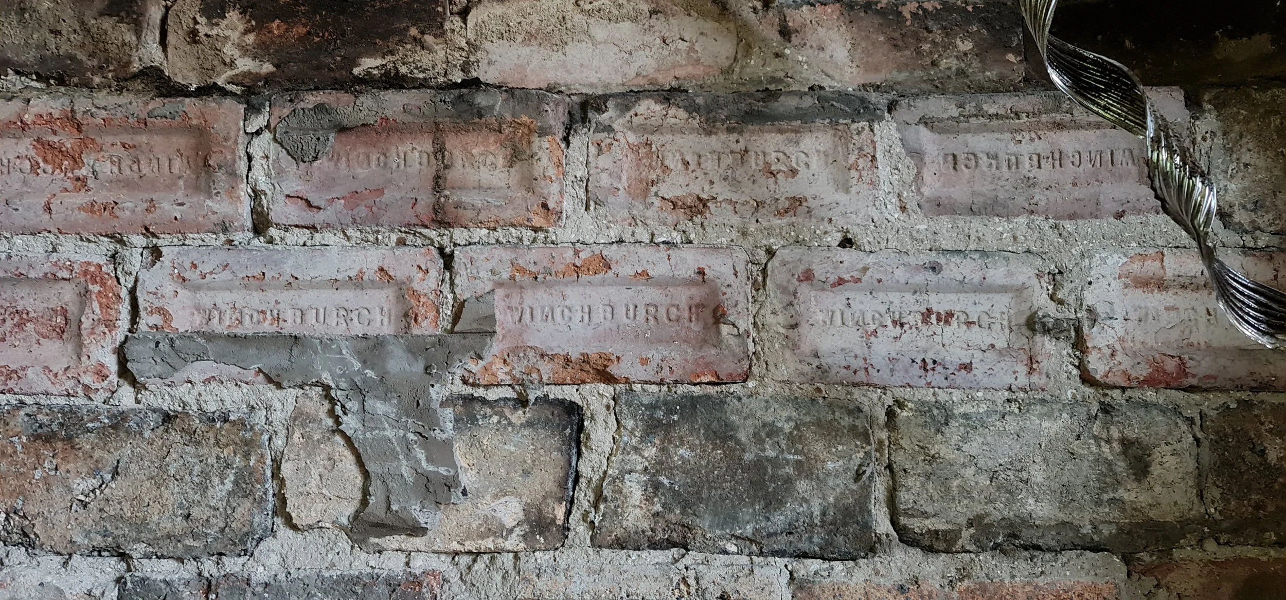 Close-up of historic brickwork with original maker’s marks in a traditional Scottish building.