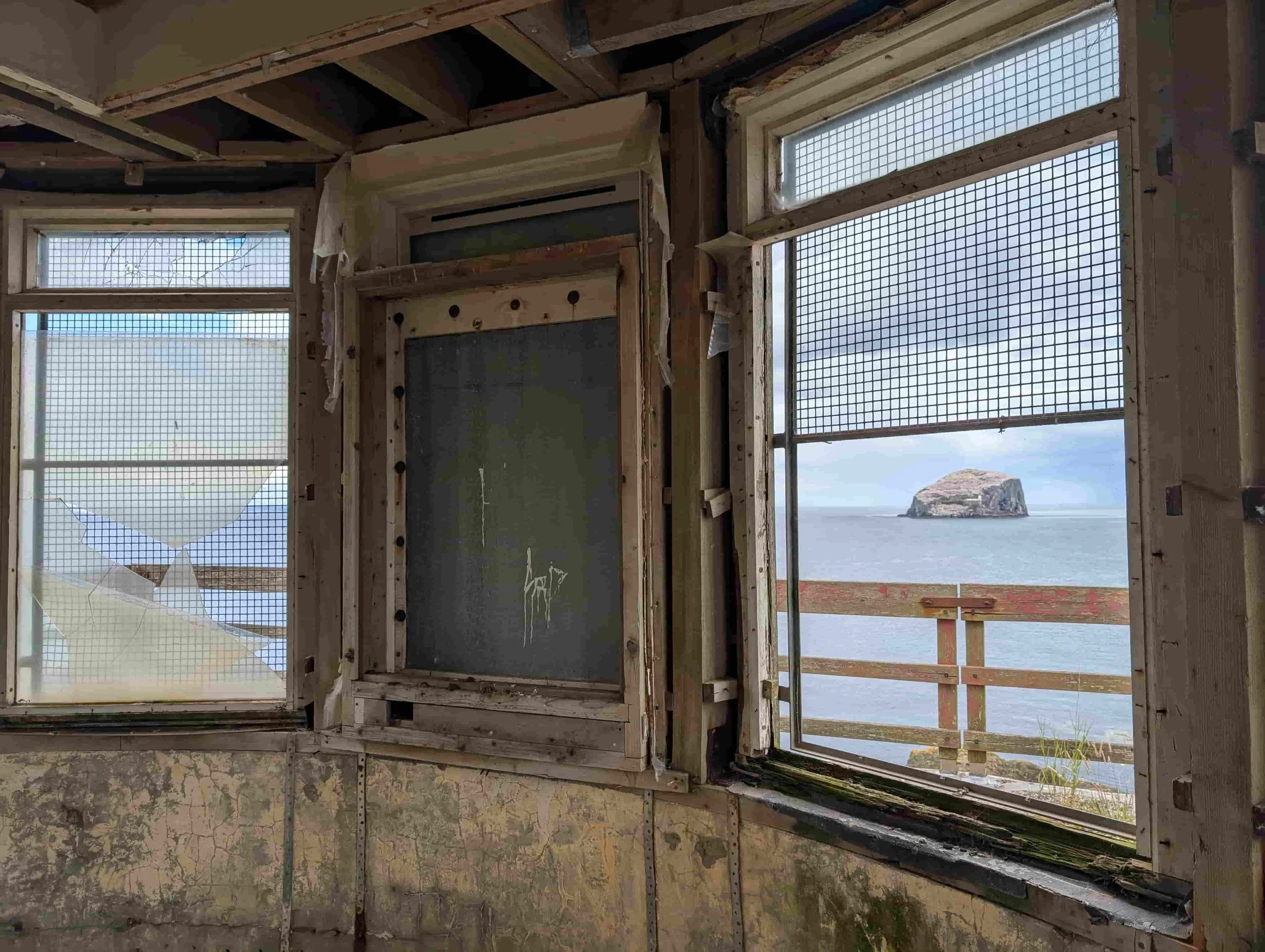 Interior of derelict coastal building with views across the sea through original windows.