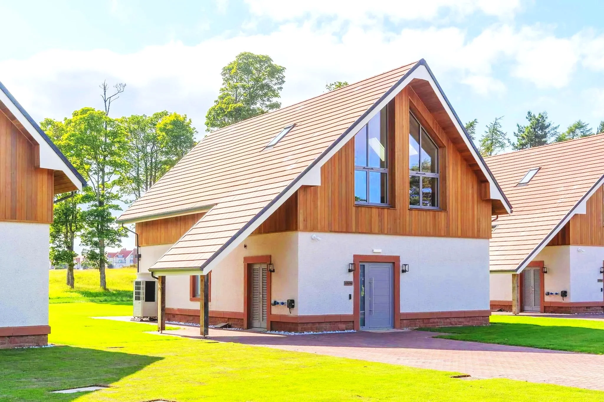 Contemporary timber-clad holiday cabin with pitched roof in landscaped setting.