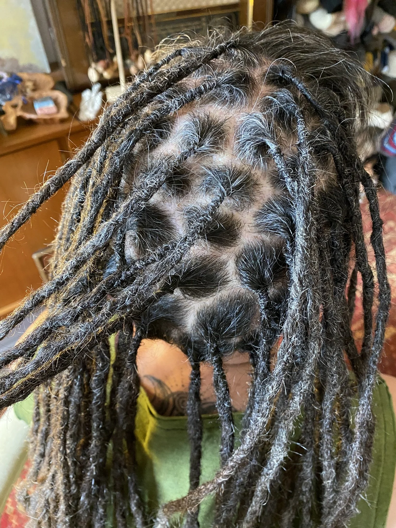 Person mit dreadlocks, die Haare wurden kürzlich gewaschen, in einem Raum mit antiken Möbeln und Dekorationen.
