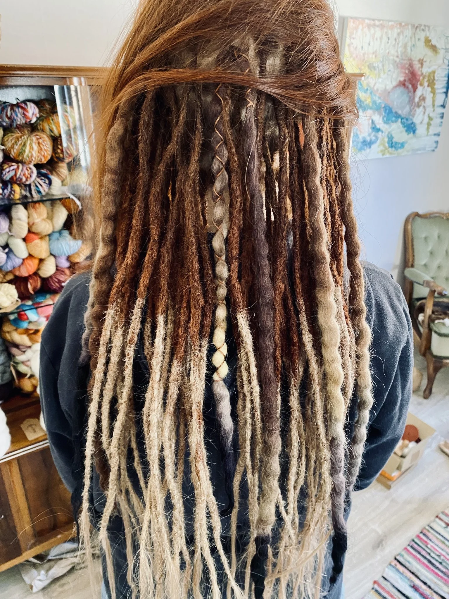 Person mit langen, geflochtenen und dreadlocked Haaren in verschiedenen Brauntönen und Beige.