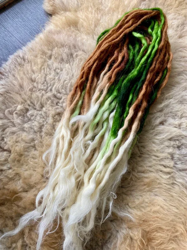 Wolle in den Farben grün, braun, beige und weiß, auf einer Felldecke