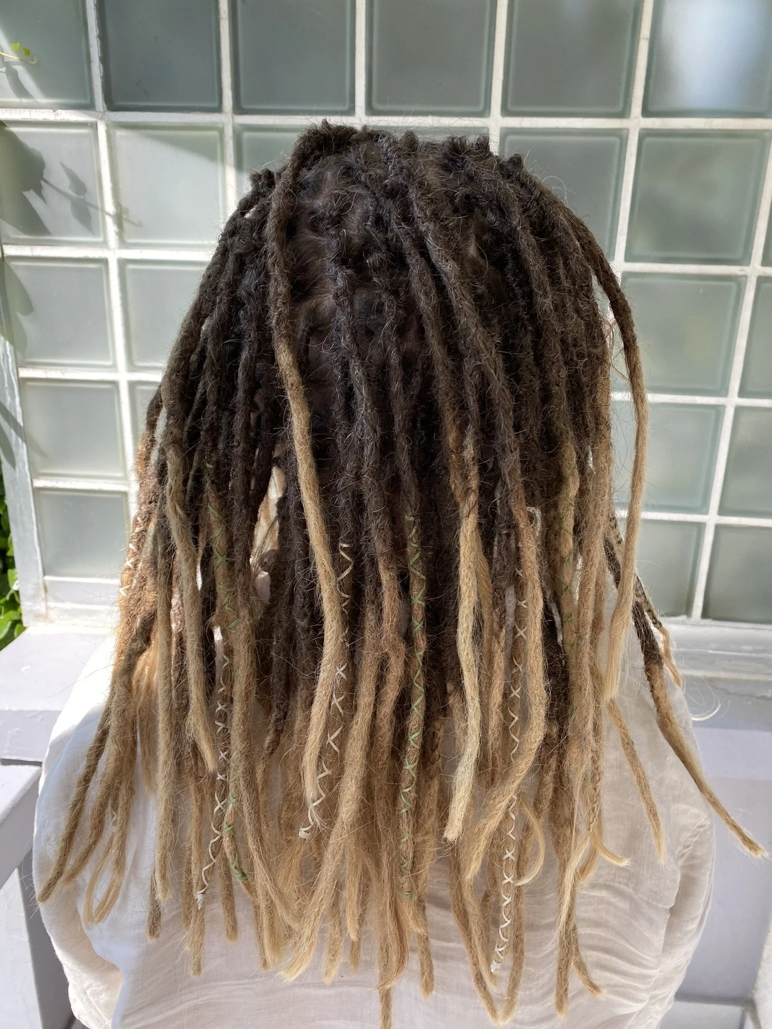 Haar mit Dreadlocks in verschiedenen Farben und Längen, teilweise mit spiralförmigen Verzierungen
