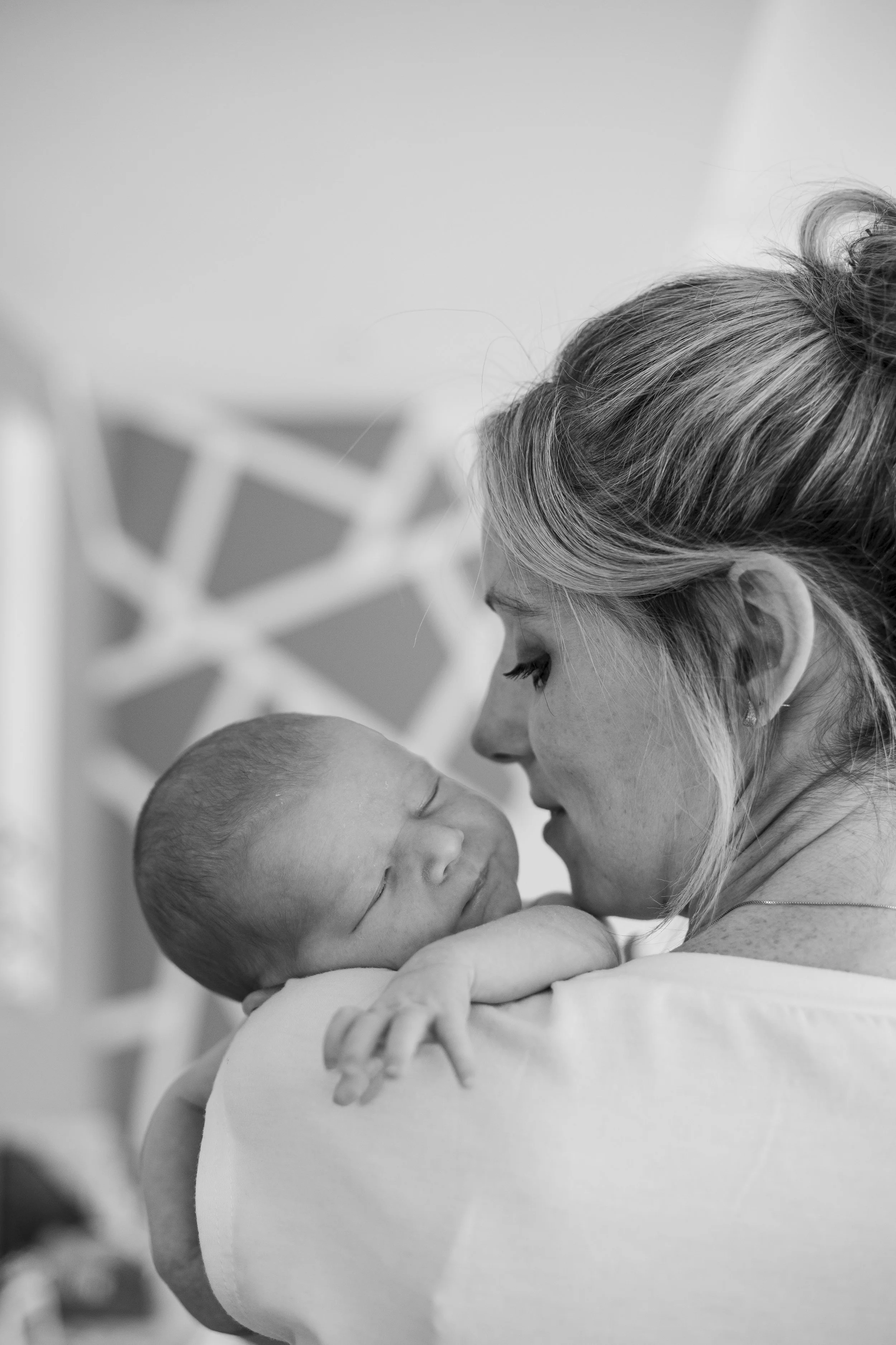 Une femme tiens un nouveau-né dans ses bras, ils se regardent tendrement, en noir et blanc.