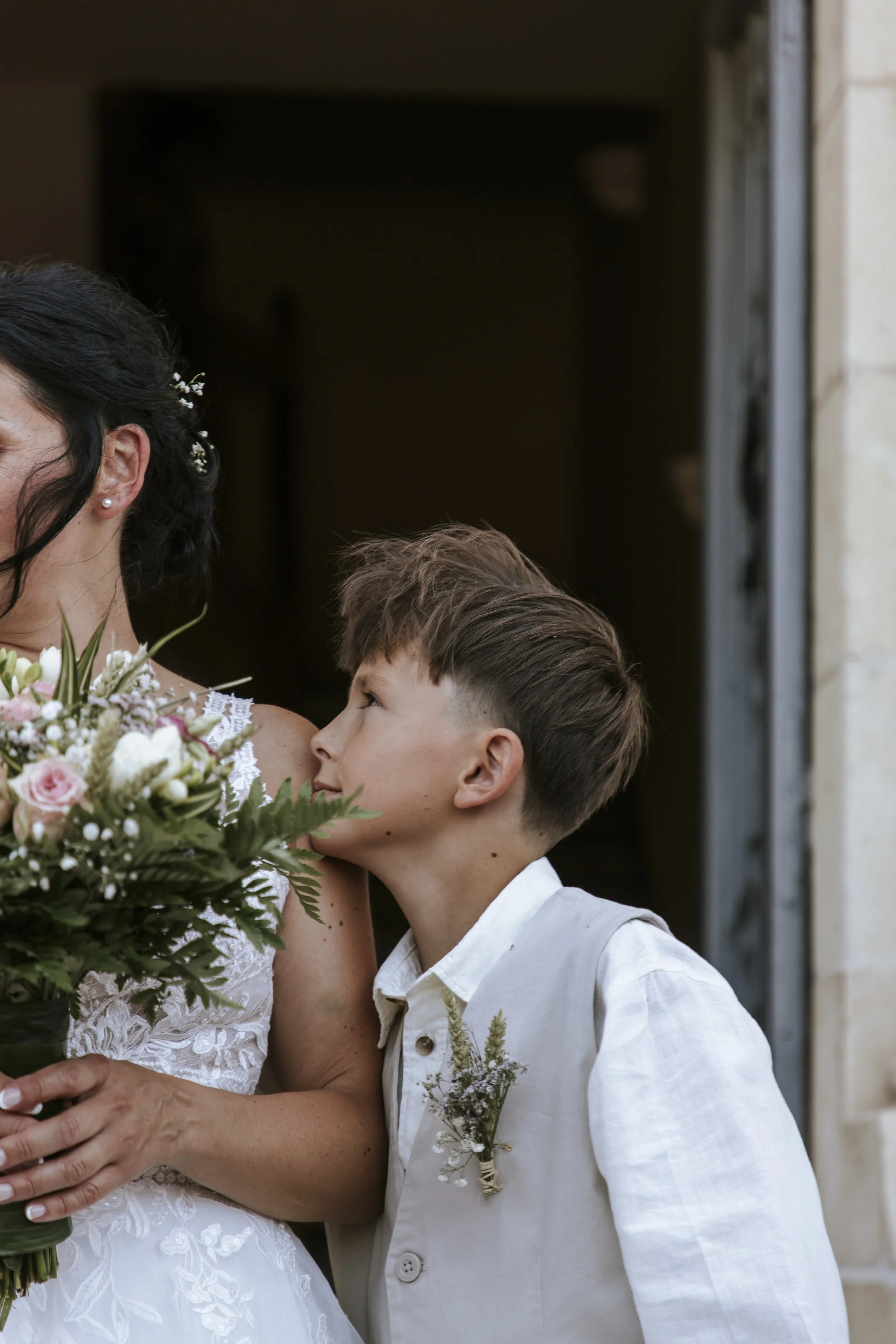 Un garçon regarde tendrement sa maman lors d'un mariage.