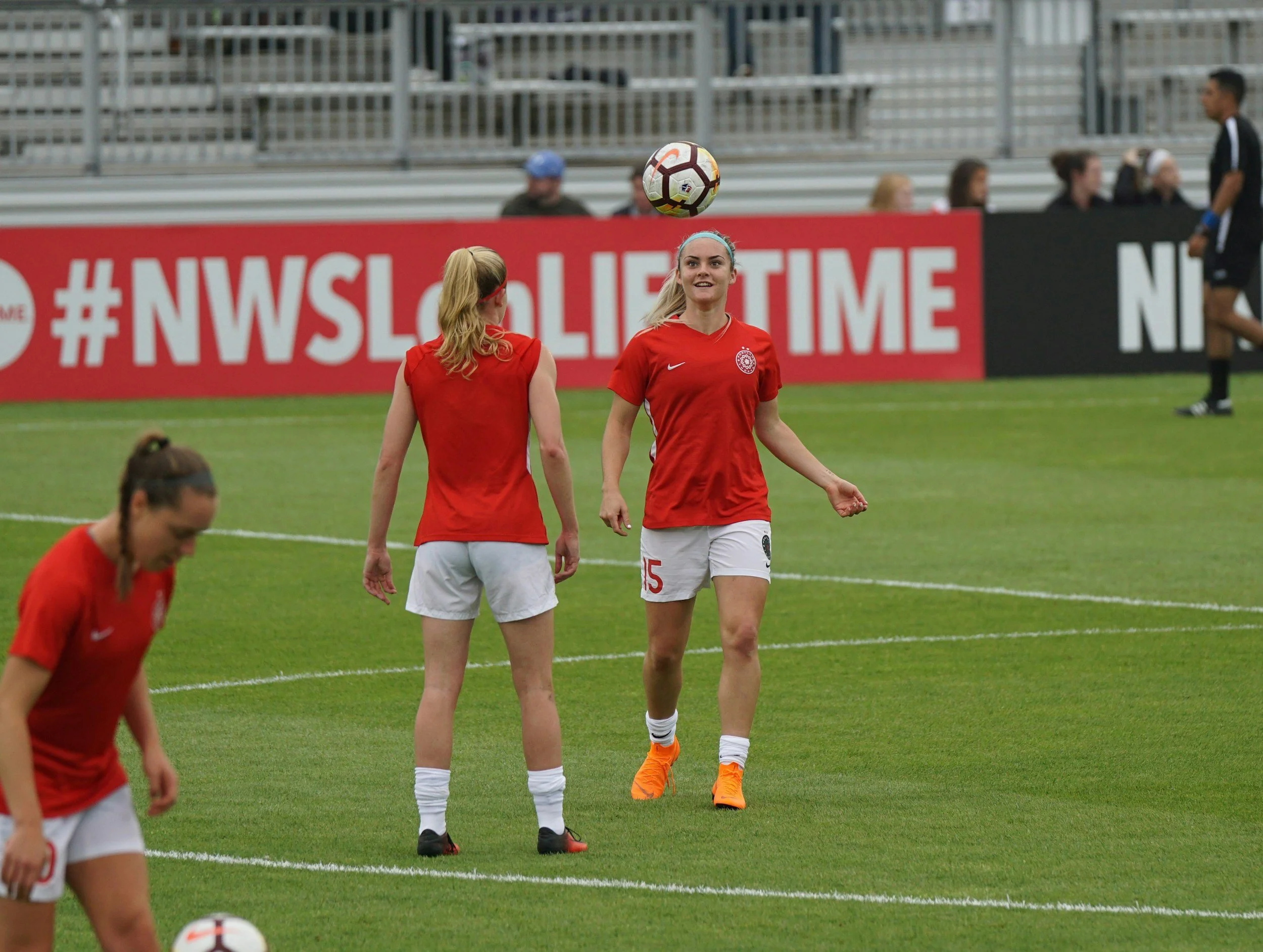 Women soccer players in red jerseys practicing on the field.