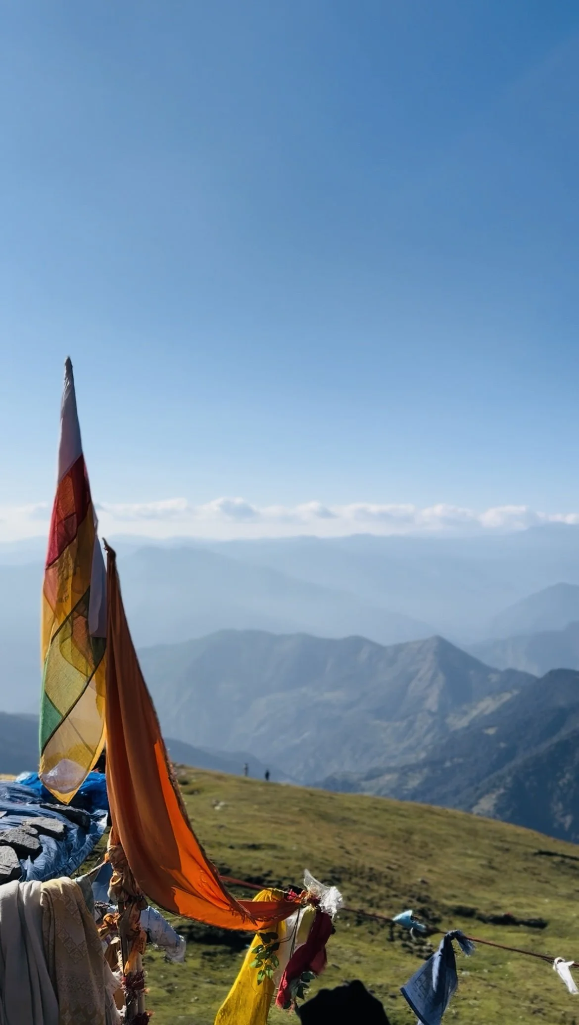 Colorful prayer flags fluttering on a mountain ridge with mountains and a blue sky in the background. Vrindavan yogi rishikesh ohmat travel himalaya debbie liladhar yoga bhakti india