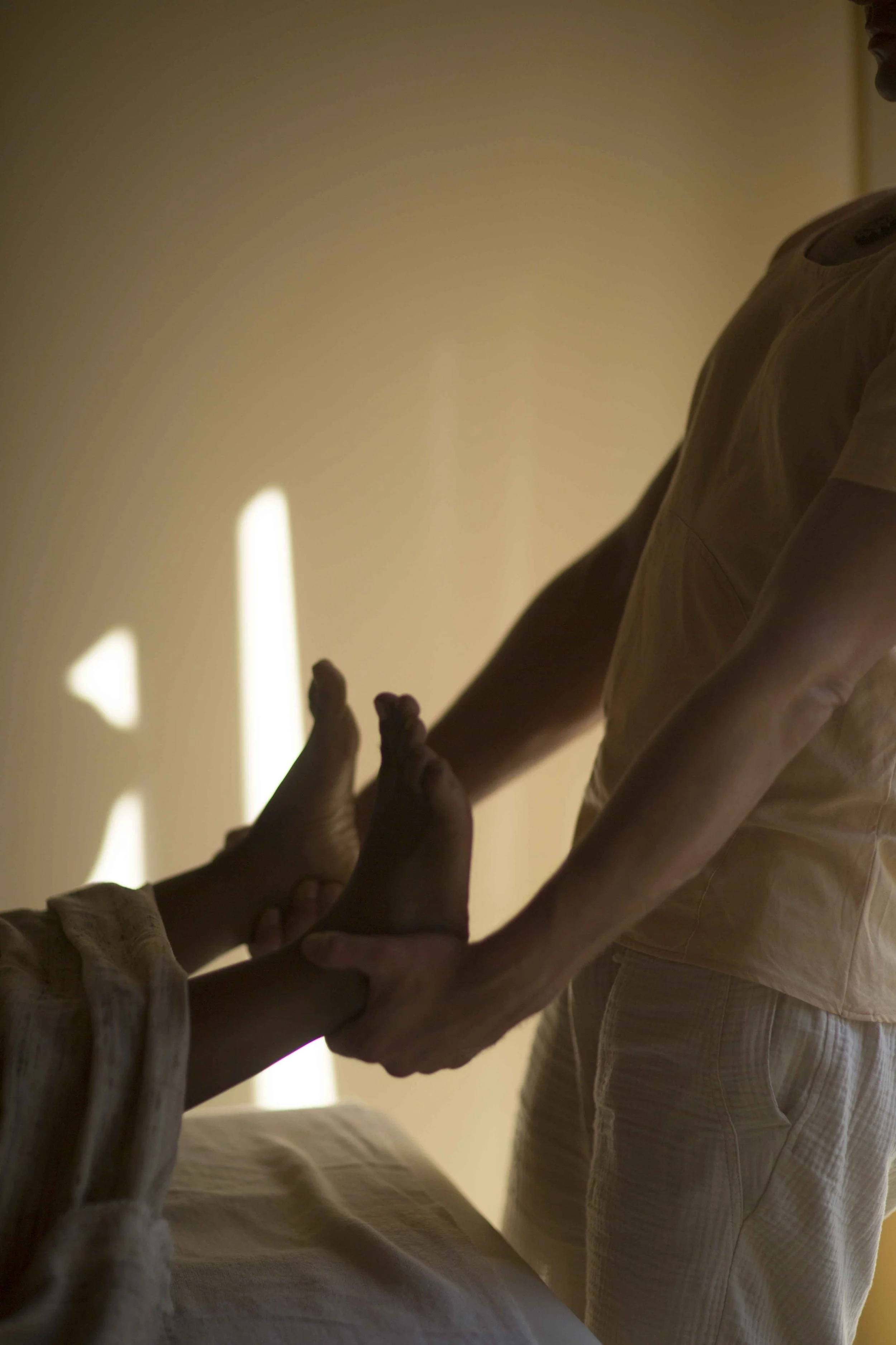 A person receiving a foot massage from another person in a softly lit room. liladhar treatment amsterdam algarve wellness meditation yoga asanas