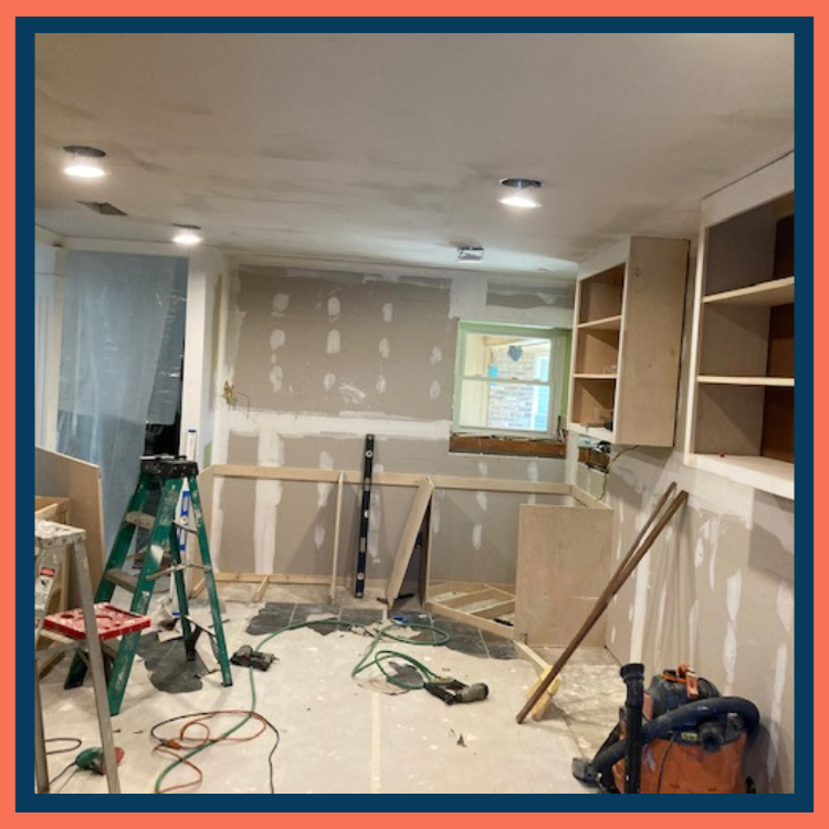 Kitchen renovation with unfinished cabinets, drywall work, tools, and construction materials.
