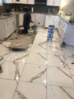 Person working on kitchen renovation, laying large marble tiles on the floor