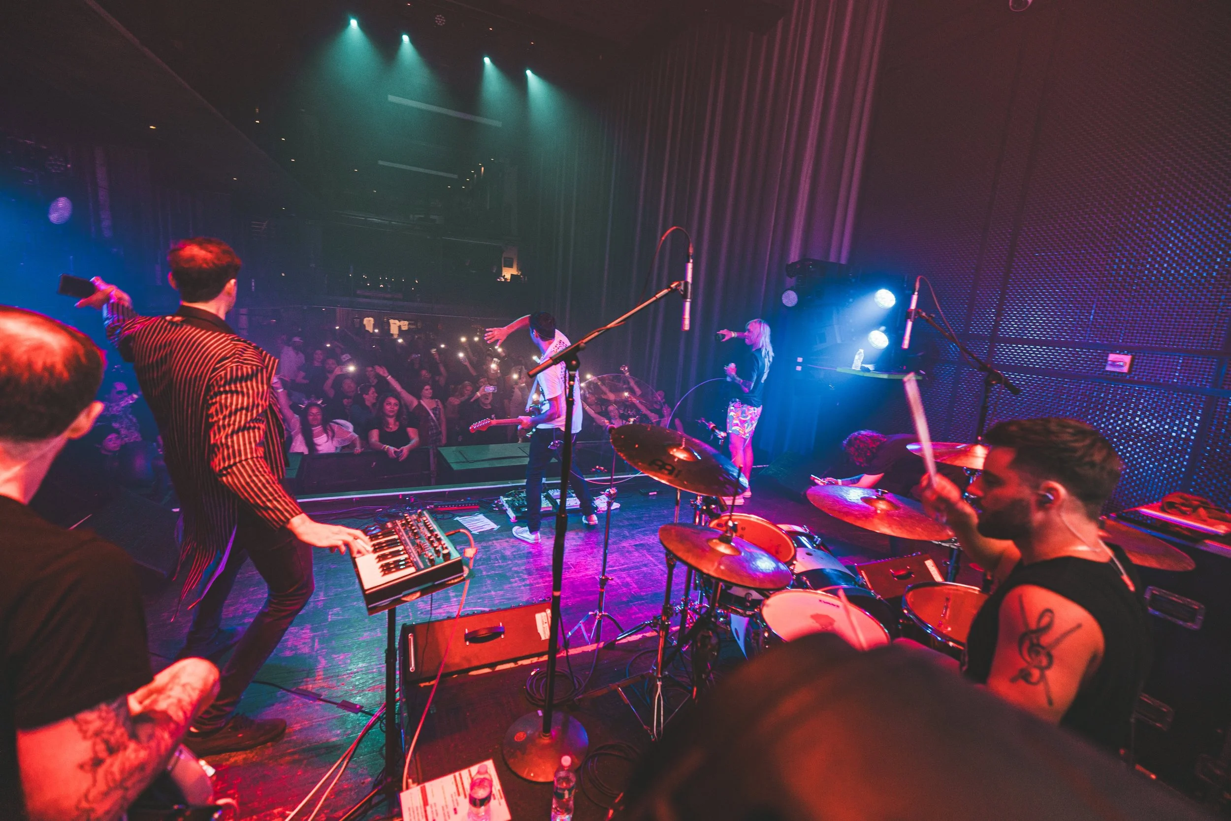 Cory Noonan drumming live behind drum riser at The Music Box in San Diego, California with Matthew Phillips and Lioneer. Photo credit Chachie.