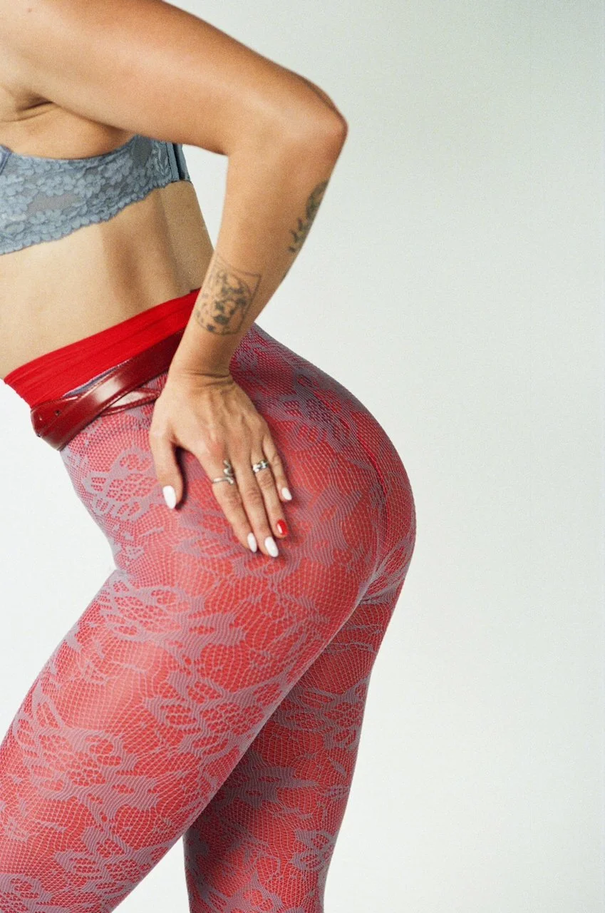 Nahaufnahme eines Frauenhüfte und Oberschenkels in roten, lacierte Leggings mit Blumenmuster