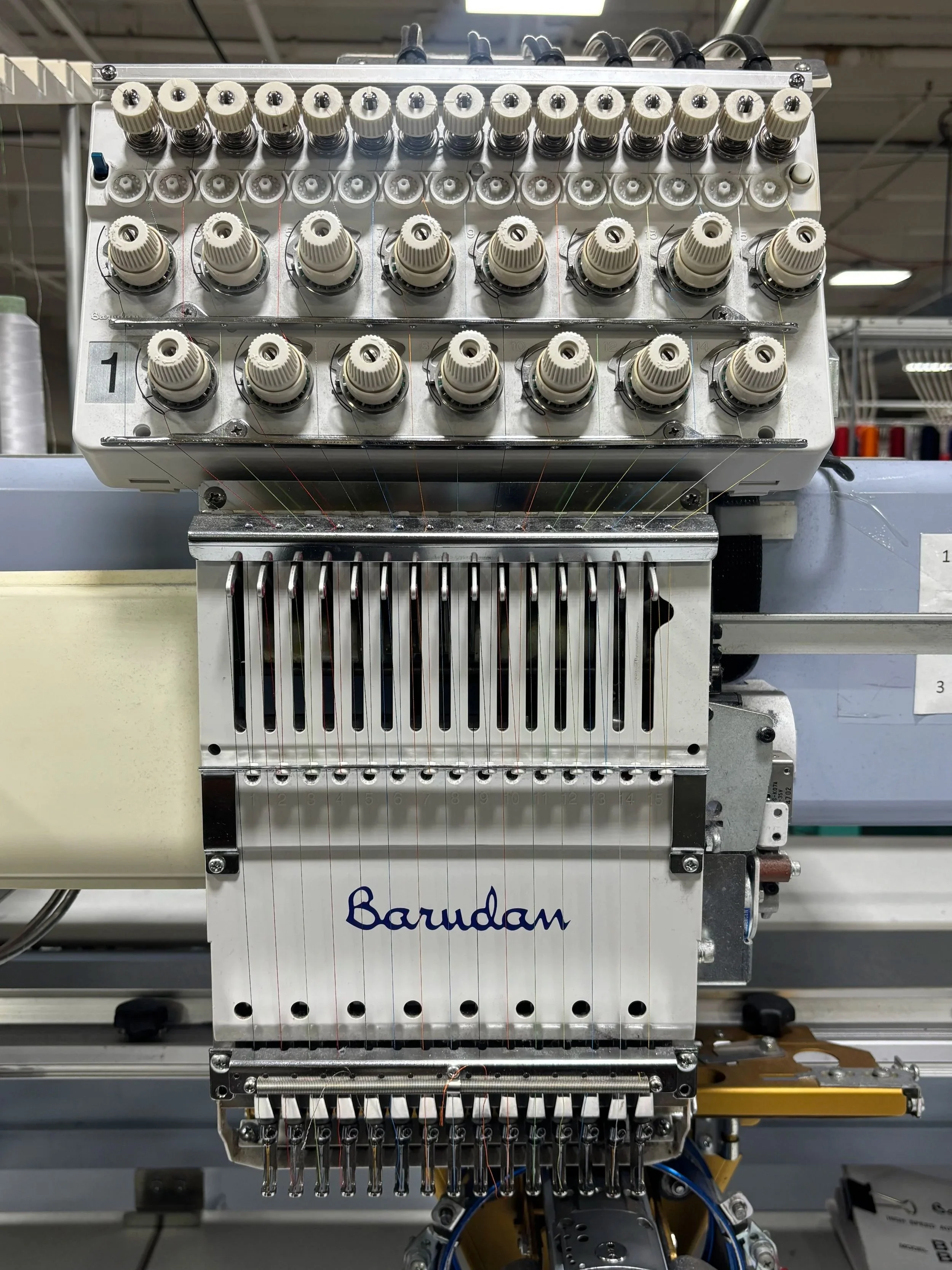 Industrial embroidery machine with multiple thread spools and colorful threads.