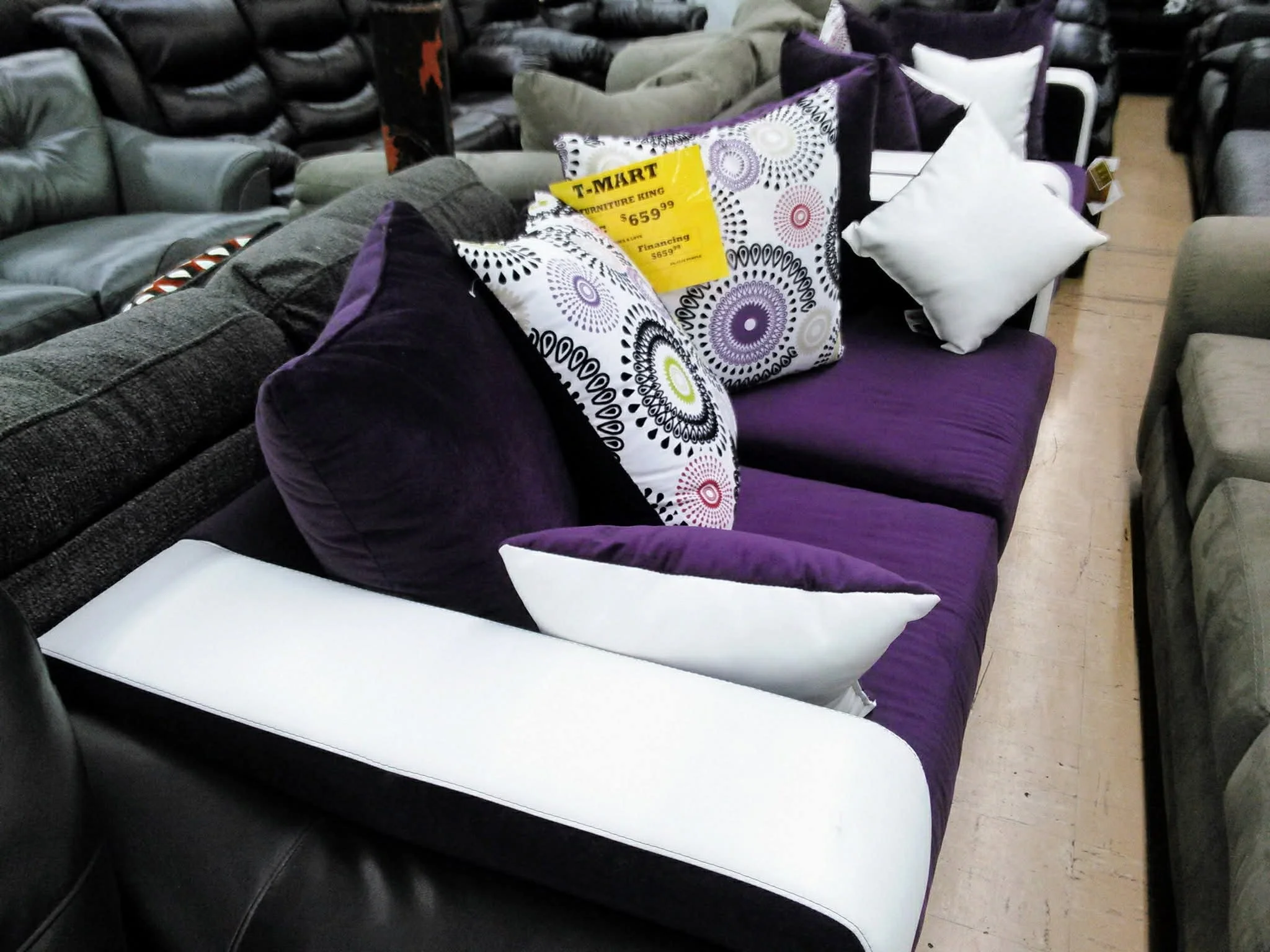 A purple sofa with various black, white, and purple decorative pillows in a furniture store display.