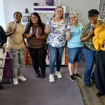 Group of six diverse women standing together in an indoor space, smiling for the photo.