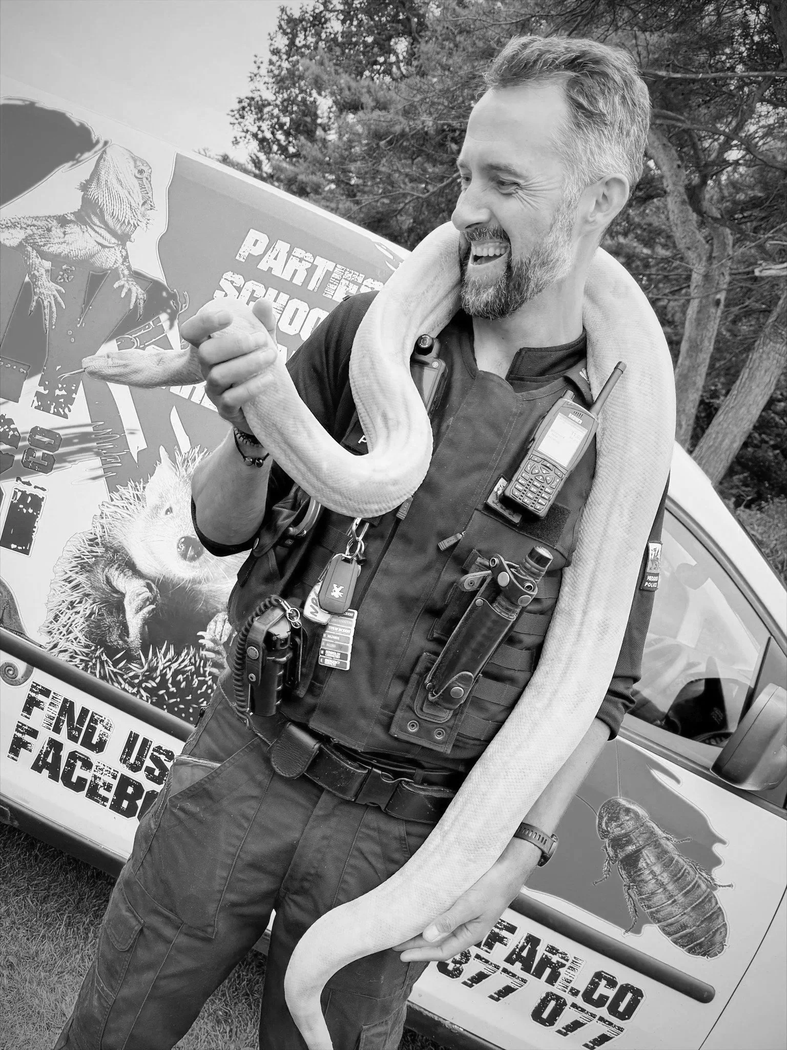 A police officer interacting with a snake at a Scaly Safari Meet & Greet, demonstrating calm, professional handling in a public event setting.