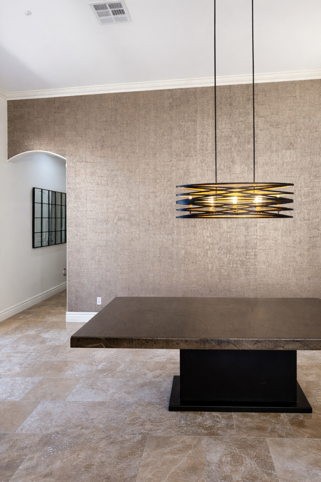 Modern dining room with a dark wood table, beige marble floor, beige textured wall, and black hanging pendant light.