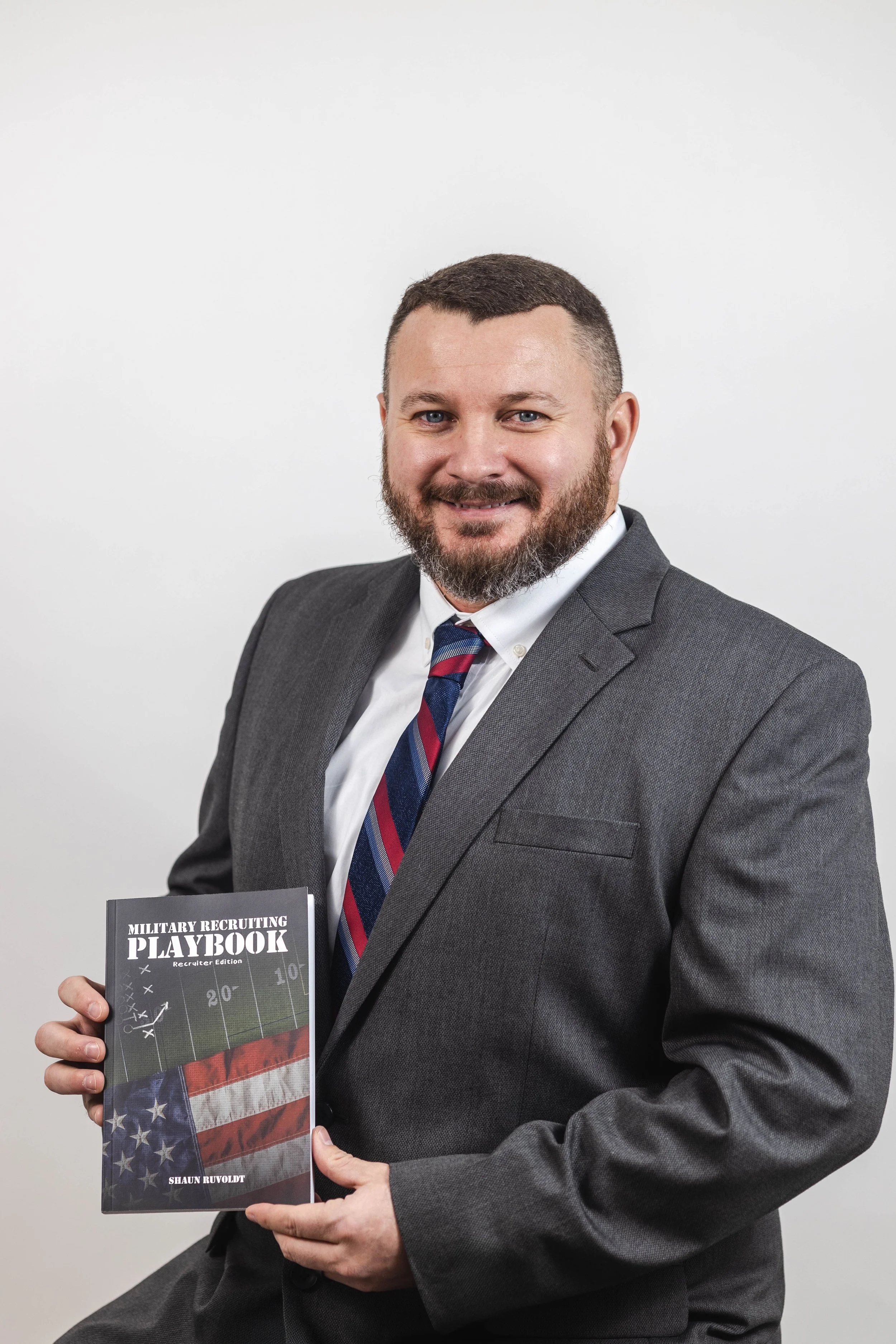 Shaun Ruvoldt holding a copy of his book titled "Military Recruiting Playbook, Recruiter Edition".
