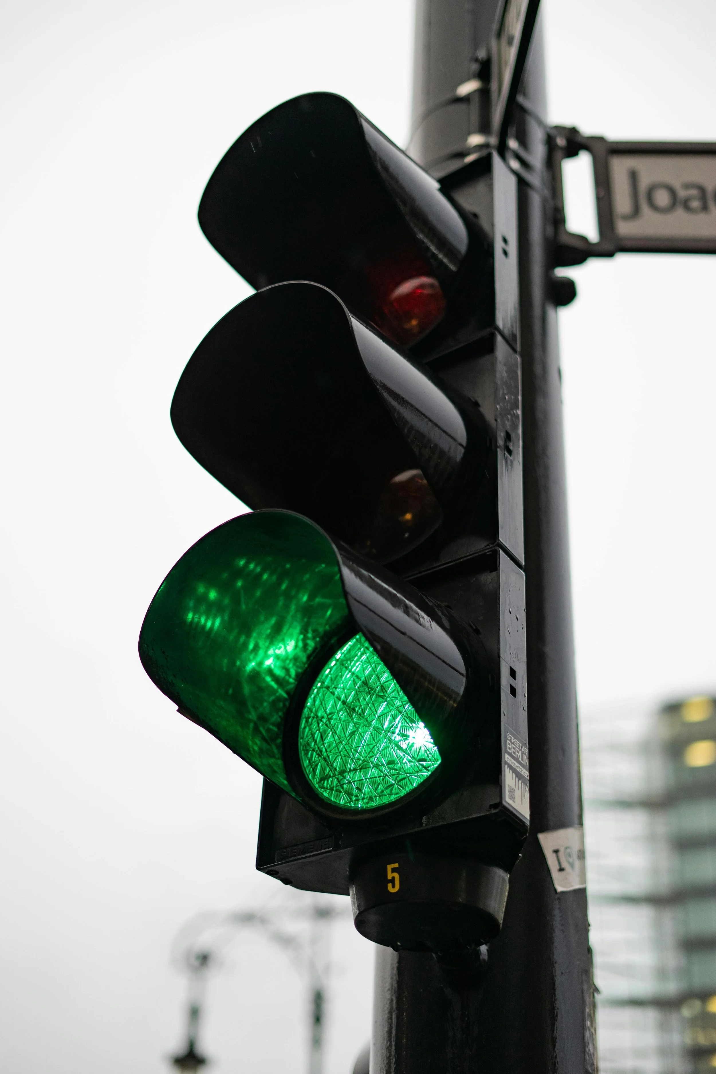 Traffic light showing green signal on a pole with a cityscape background.