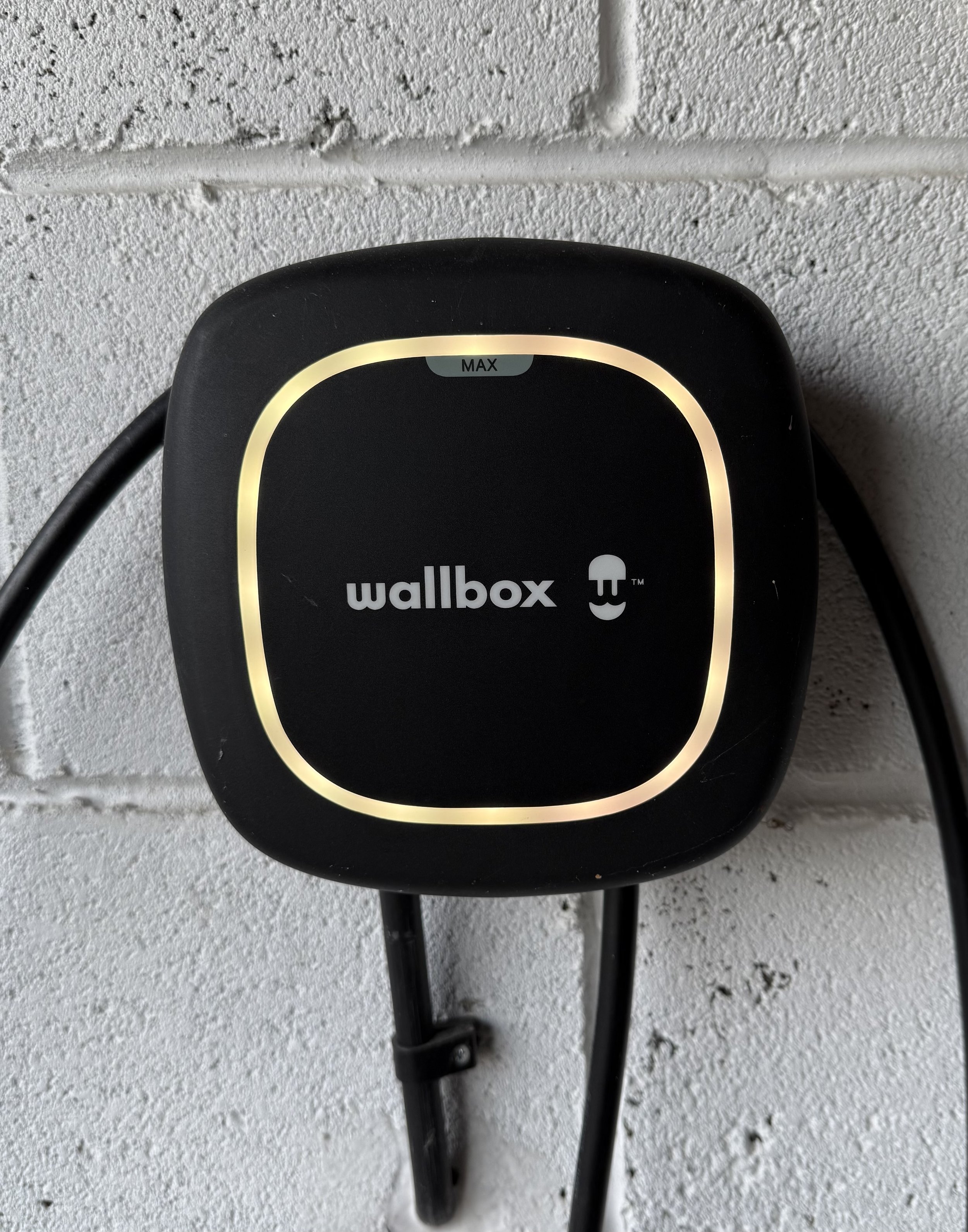 Wallbox electric vehicle charging station mounted on a white brick wall.