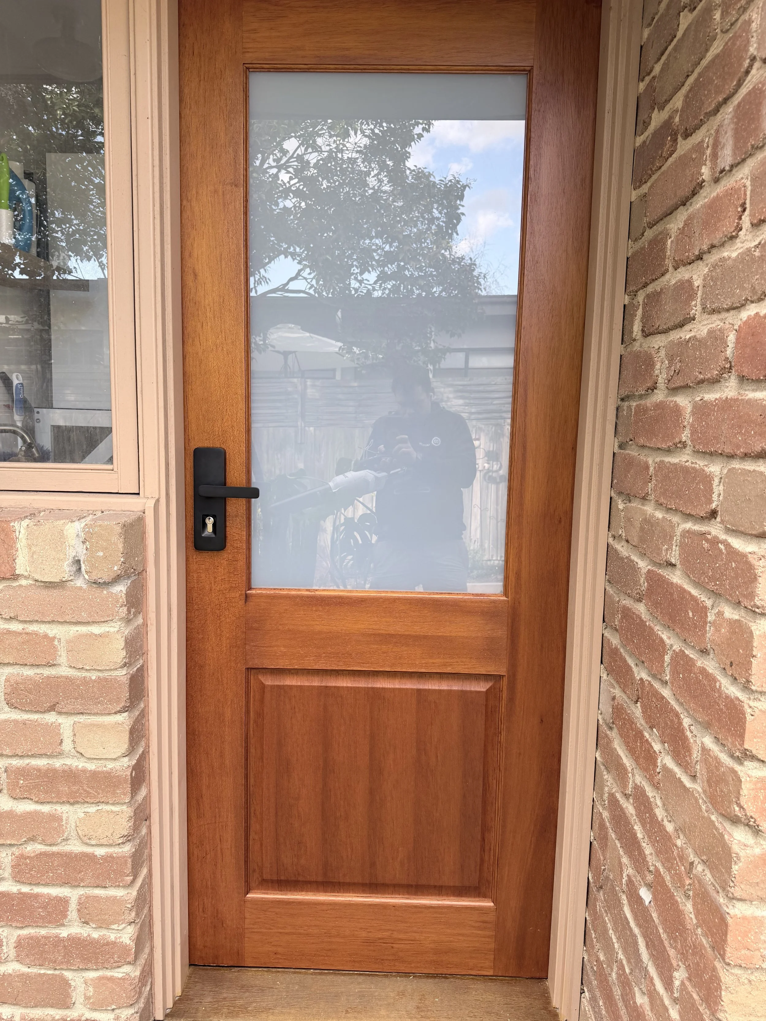 A wooden door with a glass windowpane, surrounded by brick walls on both sides.