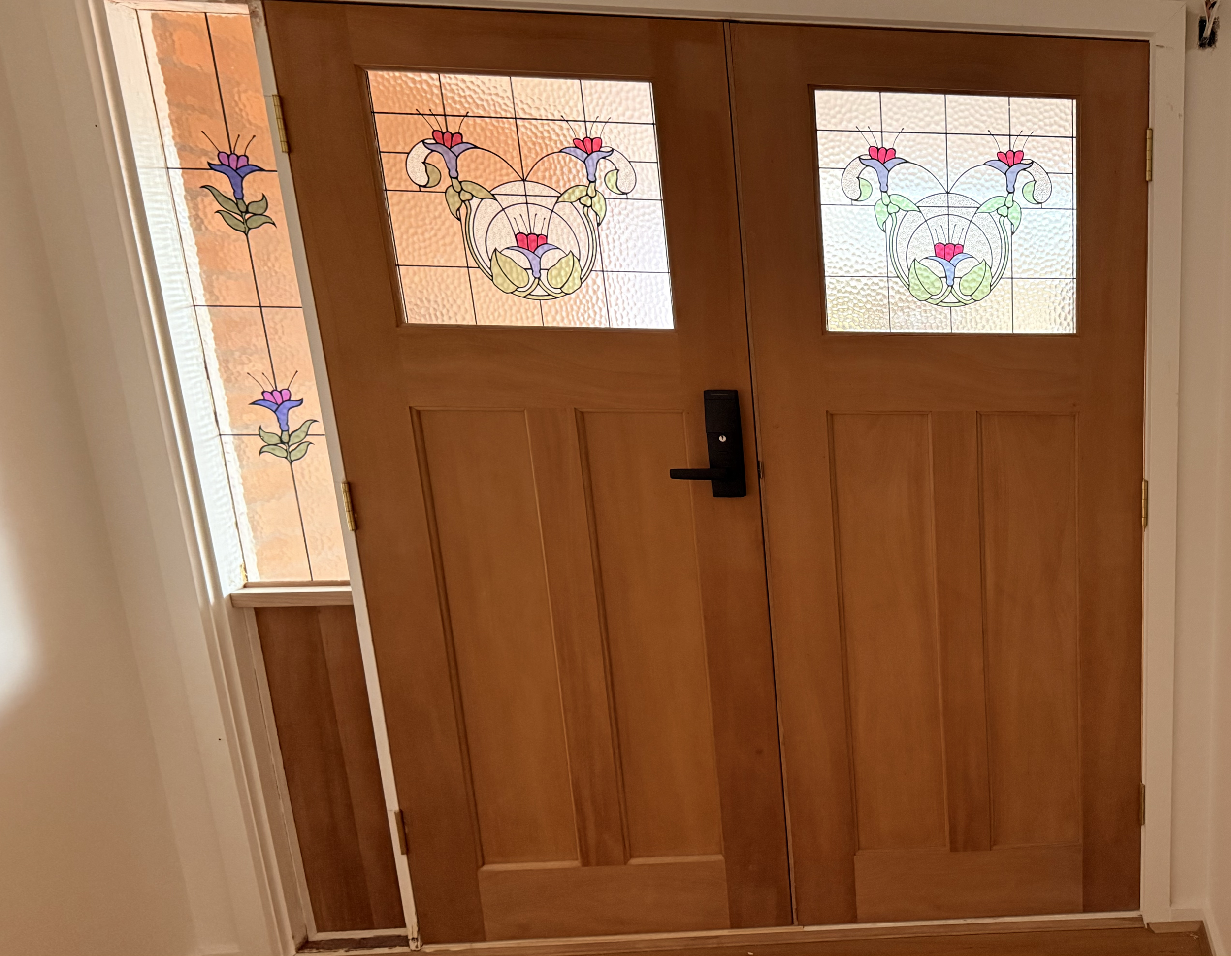 Wooden double front door with stained glass windows featuring floral designs and a wood frame.