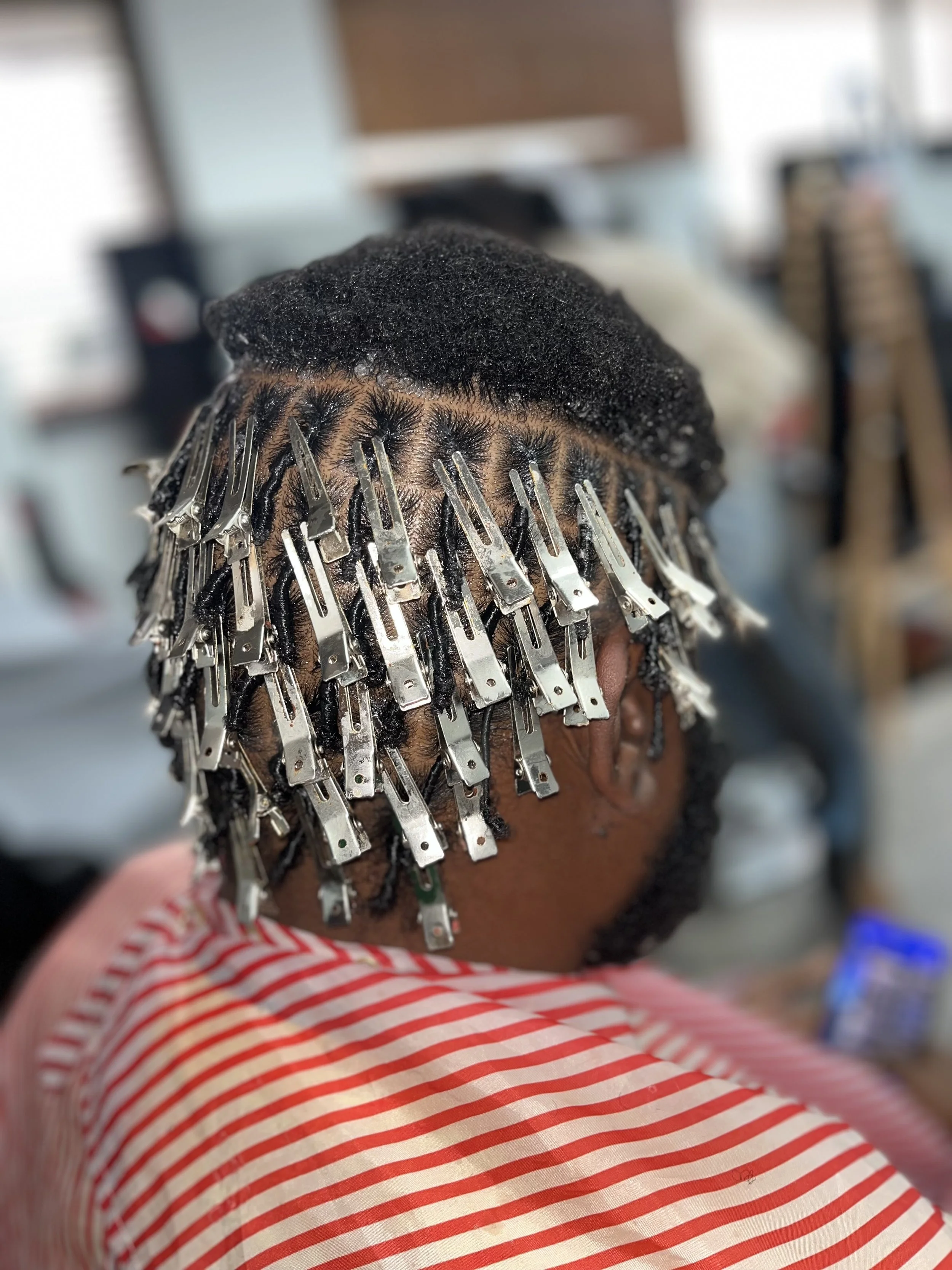 A person getting hair extensions with metallic clips in a salon.