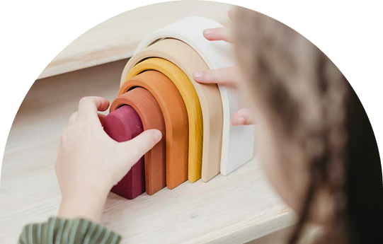 Child stacking colorful wooden arch blocks. JOY! Childcare Nanny Agency in London, UK.