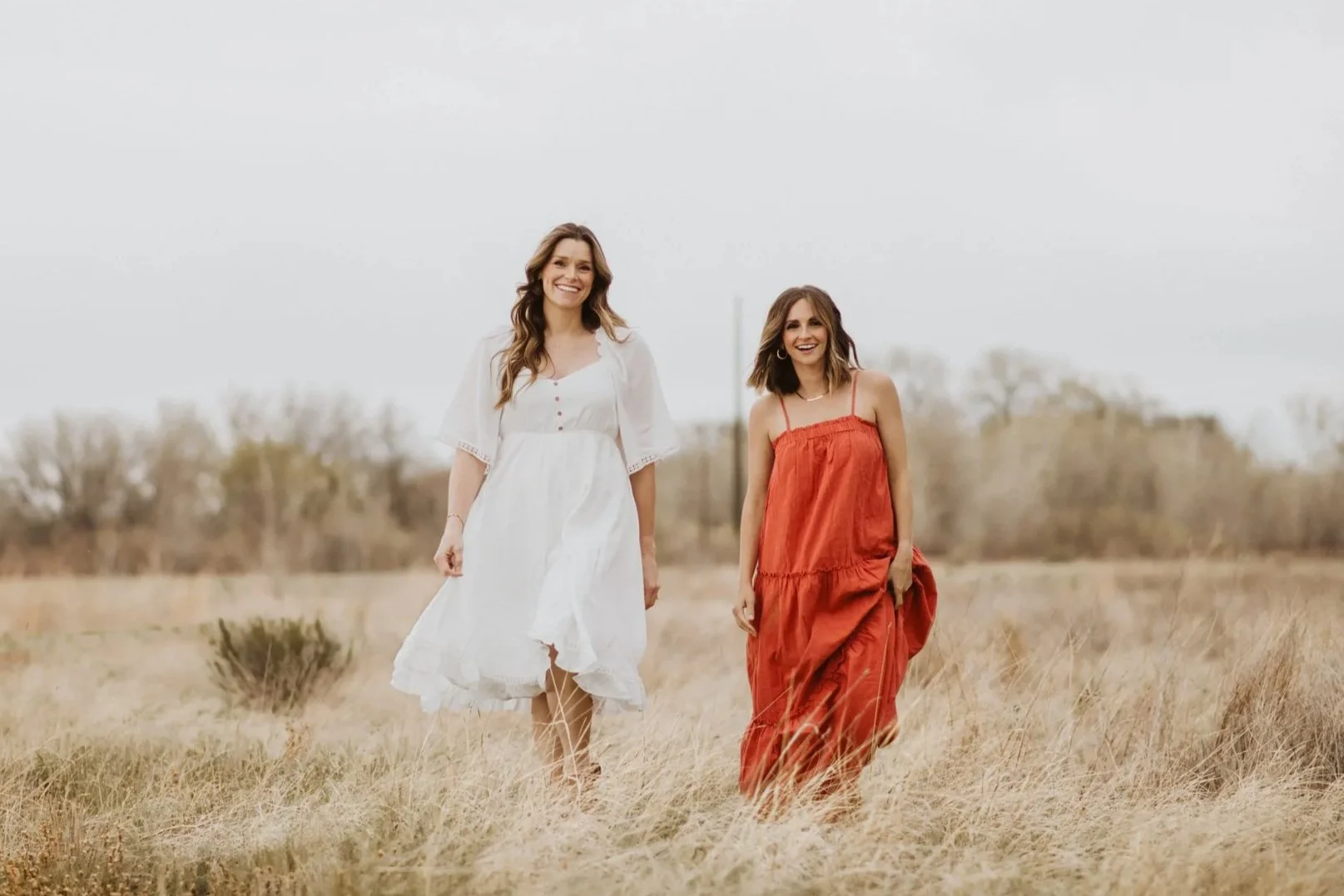 Hannah Dorsher and Kelly Sinning, licensed therapist for moms and women in fort collins colorado walking in a field in a white and orange dress, smiling