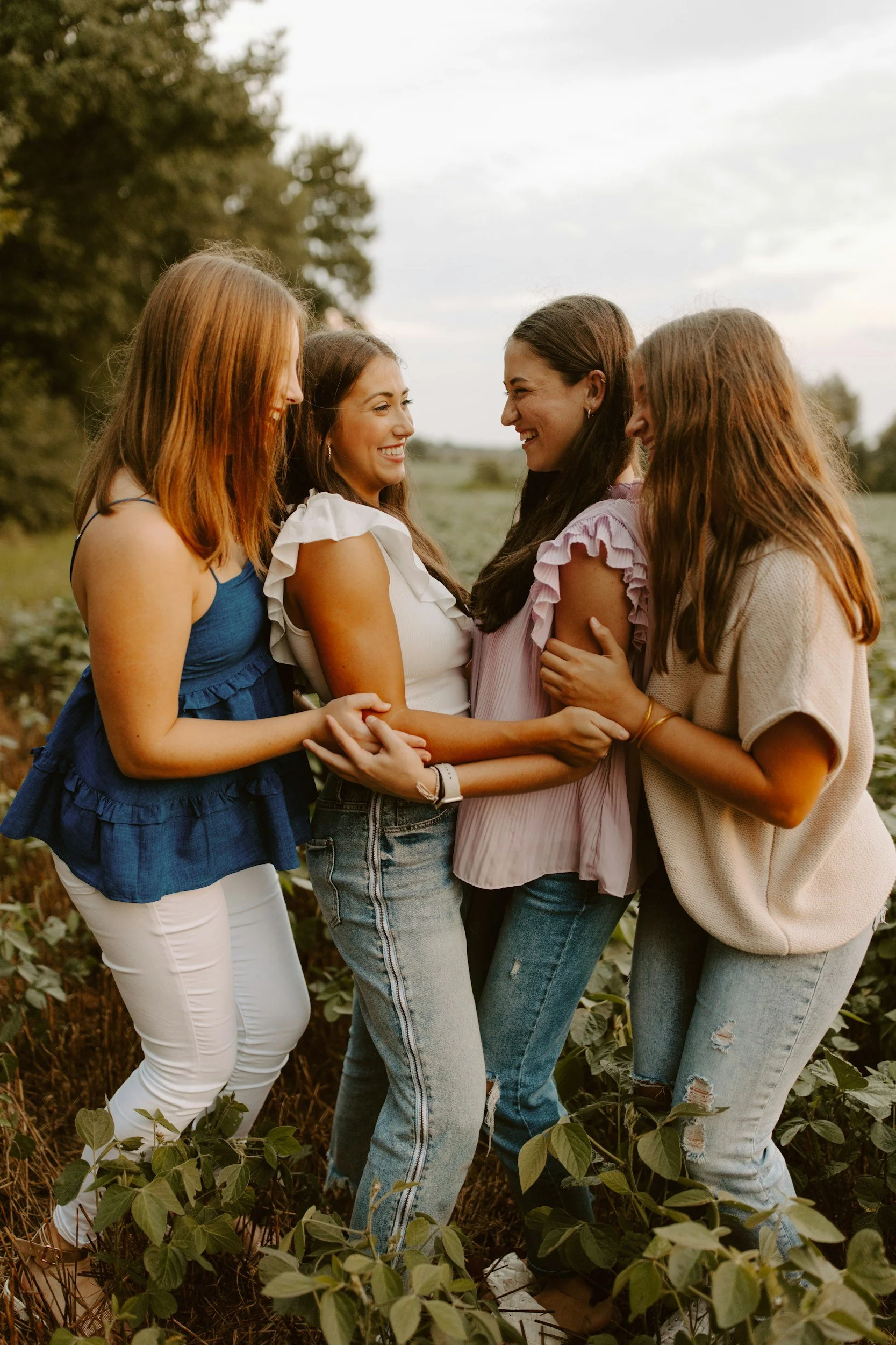 four women in a field, smiling and holding arms, therapy for postpartum fort collins colorado