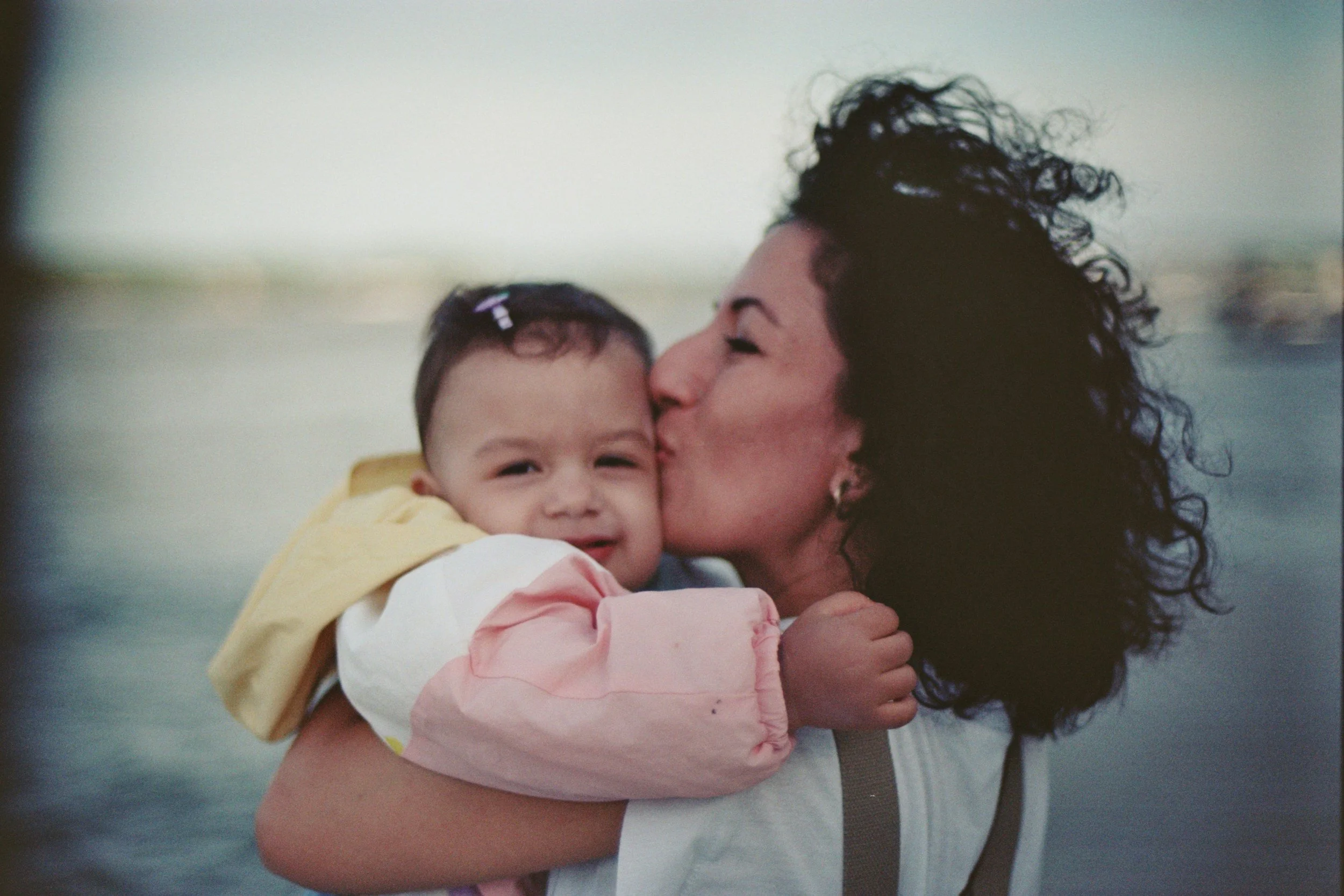 therapy for perfectionism and anxiety in motherhood, mom holding baby and kissing her cheek