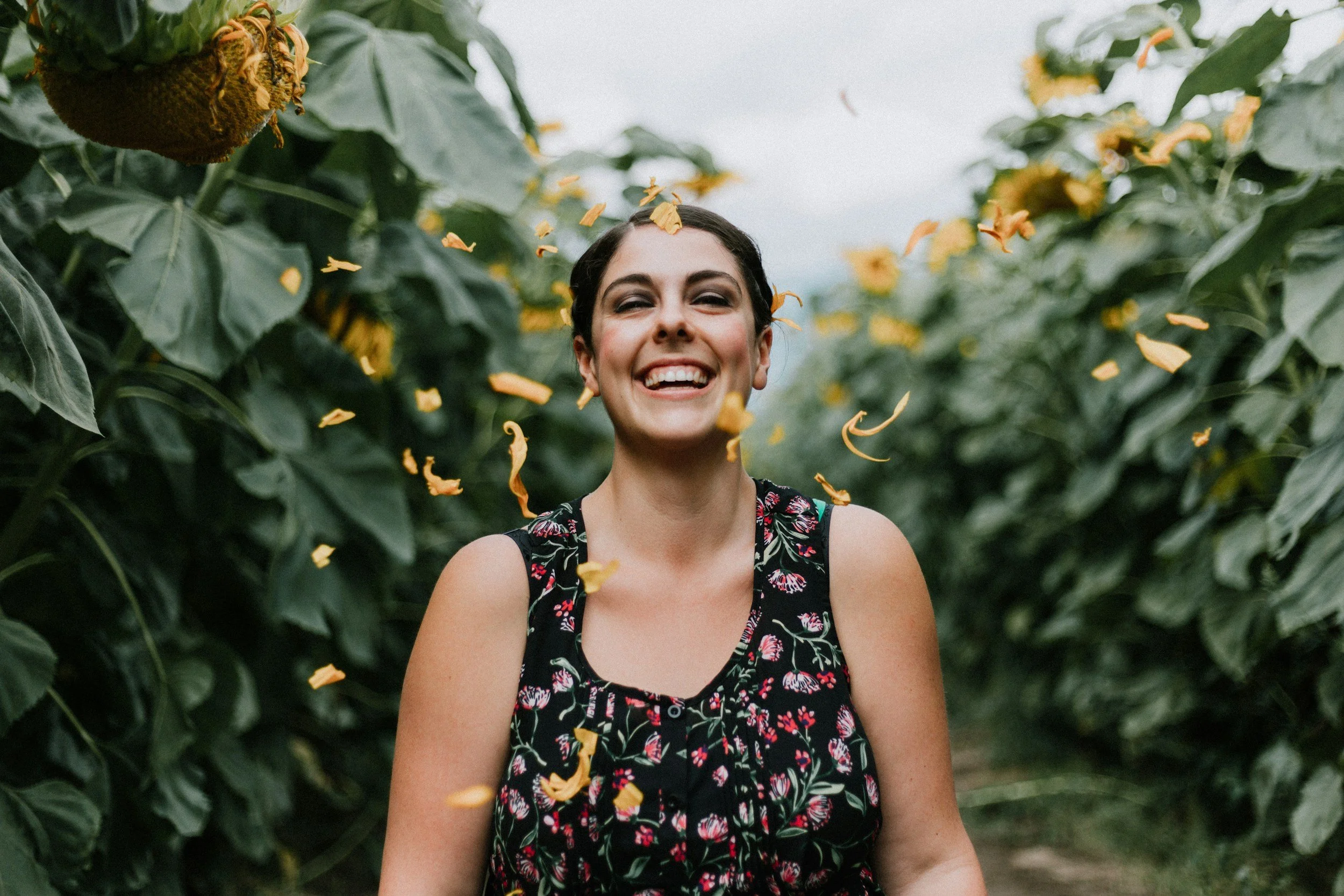 therapy for postpartum stress, anxiety and perfectionism, woman smiling in a sunflower field