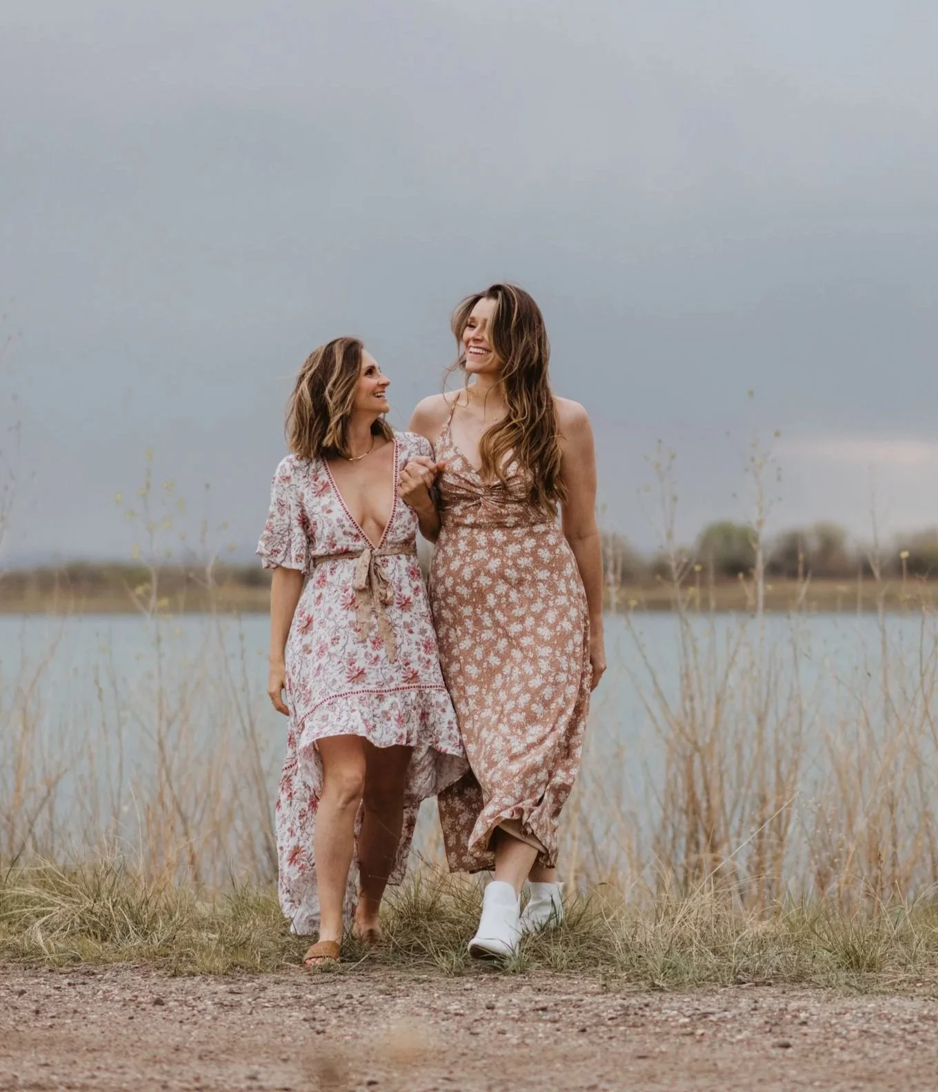 Kelly Sinning and Hannah Dorsher walking, arm in arm, in dresses by a lake, therapists for relationship issues in fort collins colorado