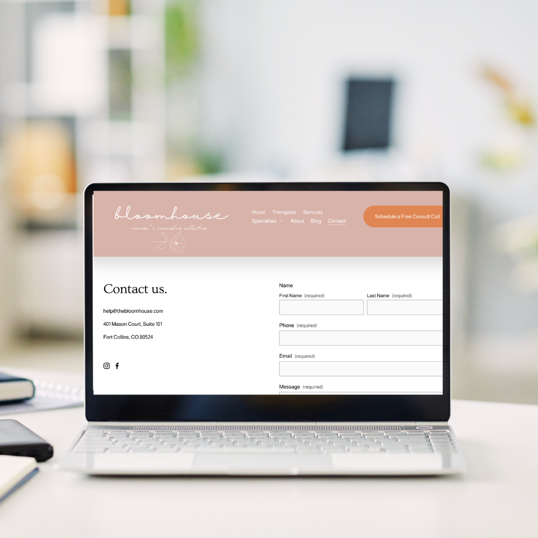 Laptop displaying a therapy practice's contact form on a clean, white desk in a bright, modern office.