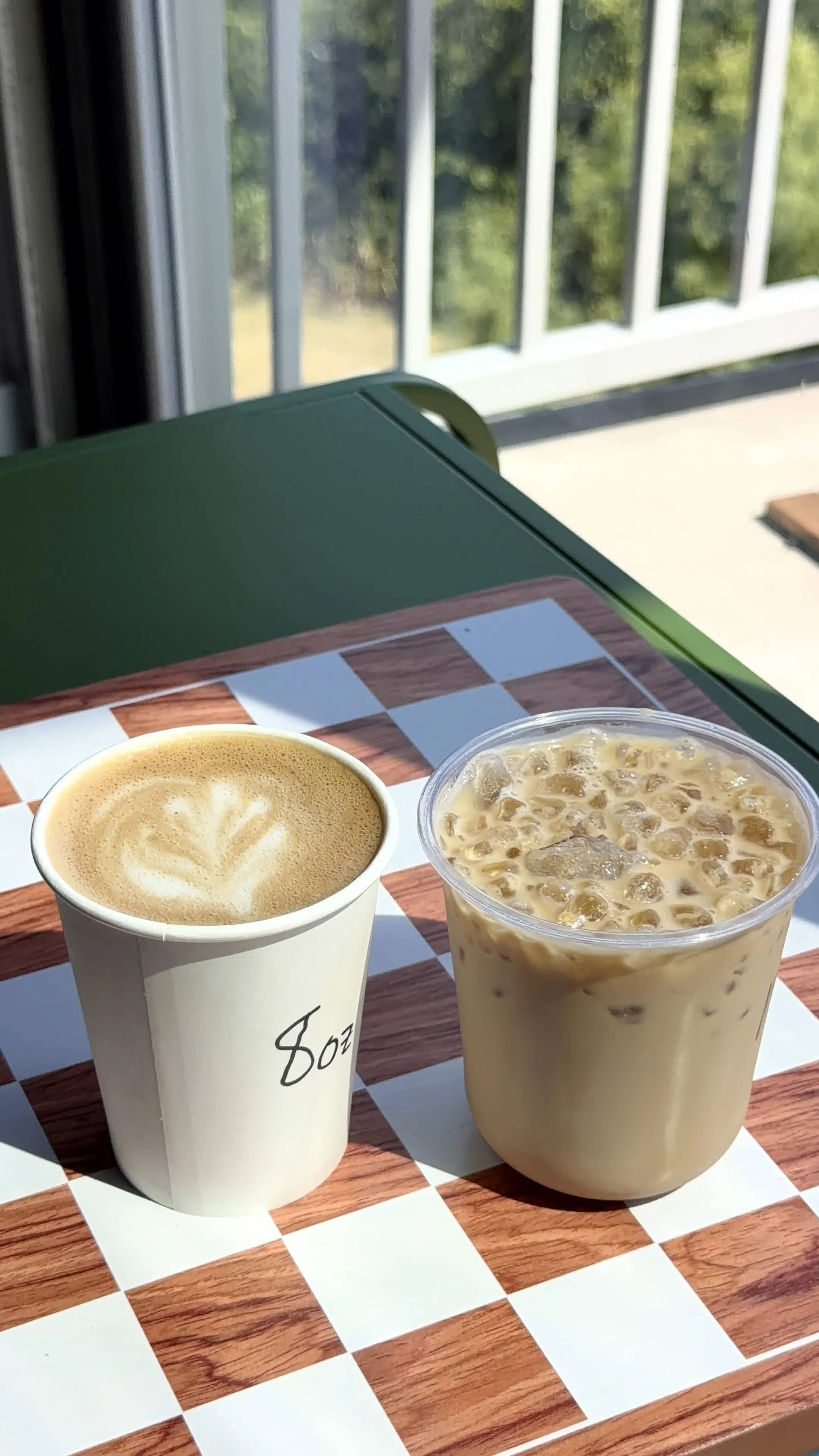 A picture of an iced latte and hot latte with tulip latte art.
