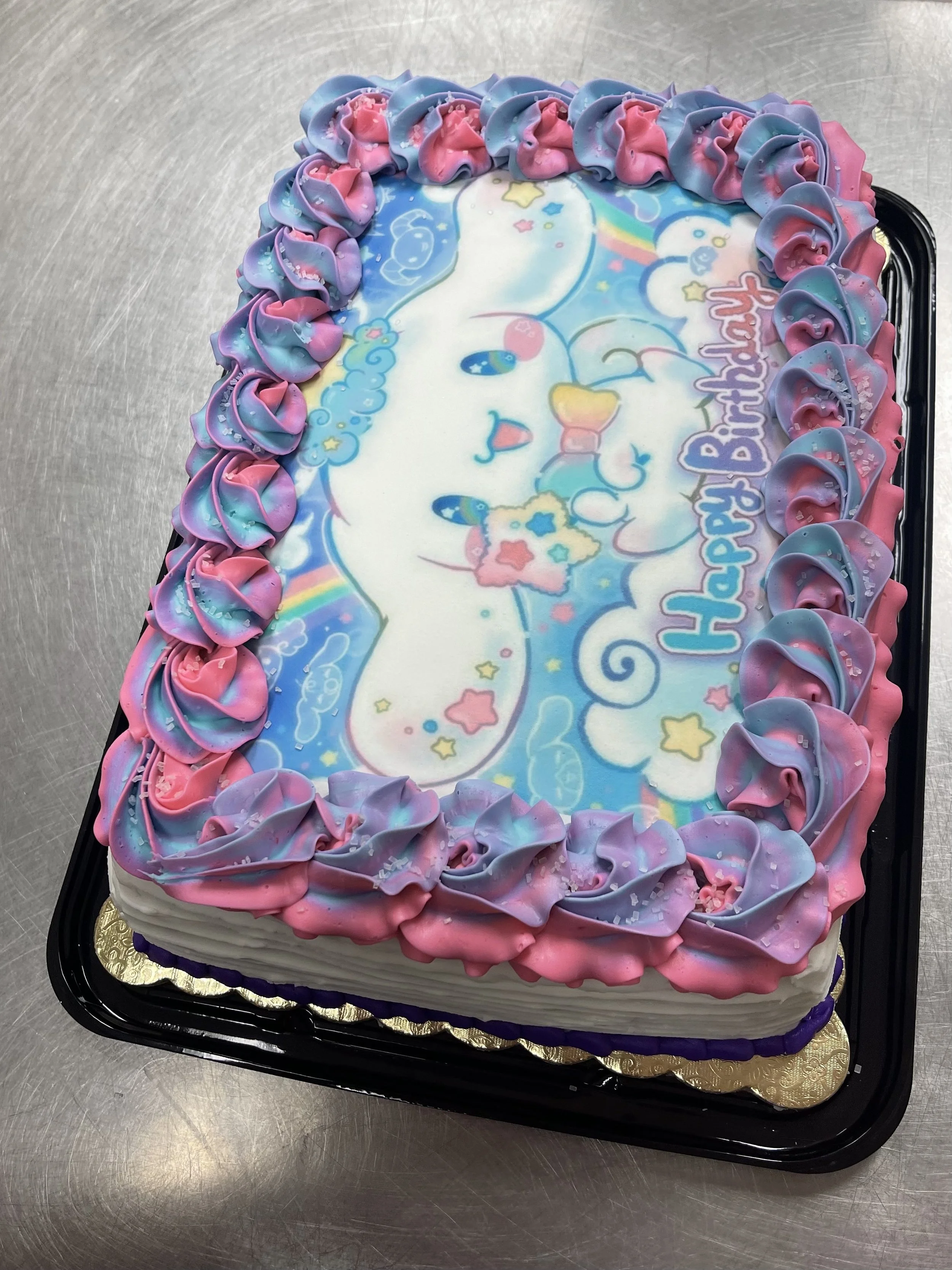 Colorful birthday cake with an animated unicorn design on top, pink and purple frosting, and a message that reads 'Happy Birthday'.