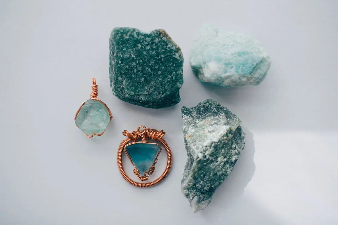 Three pieces of raw turquoise and two wire-wrapped turquoise pendants on a white background.