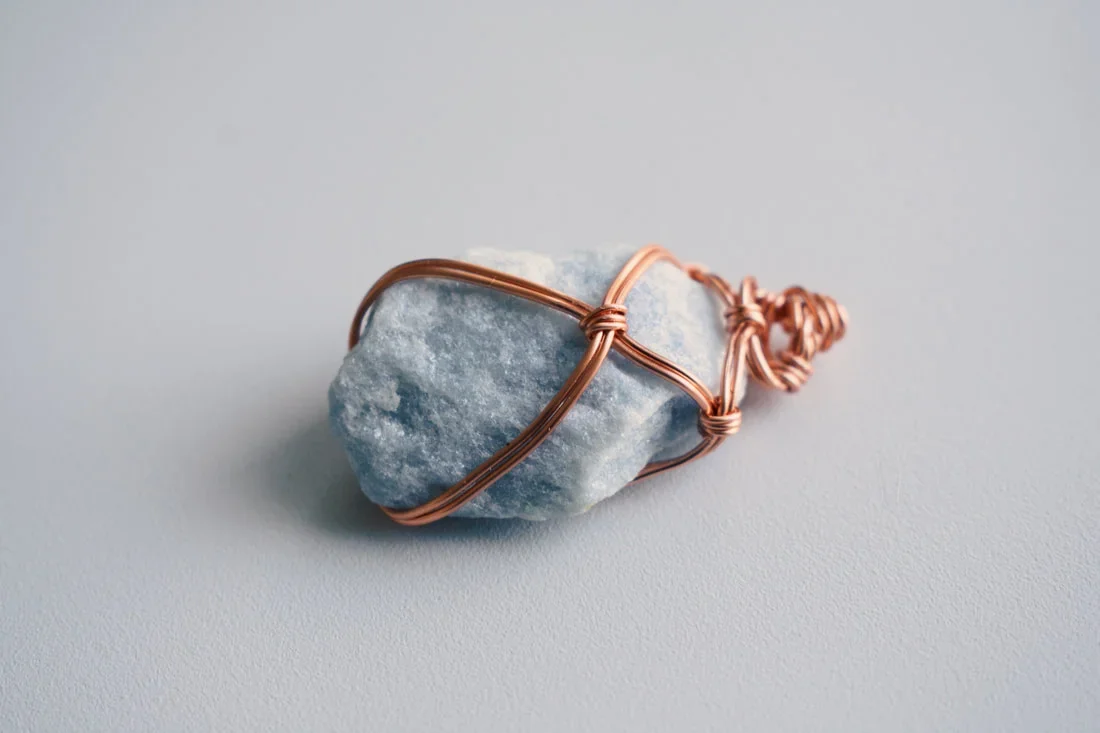 A blue stone wrapped in copper wire.