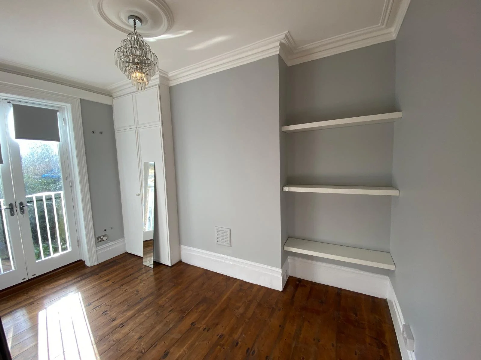 Freshly painted grey bedroom with built-in shelving and feature wall completed by a painter and decorator in Ware.