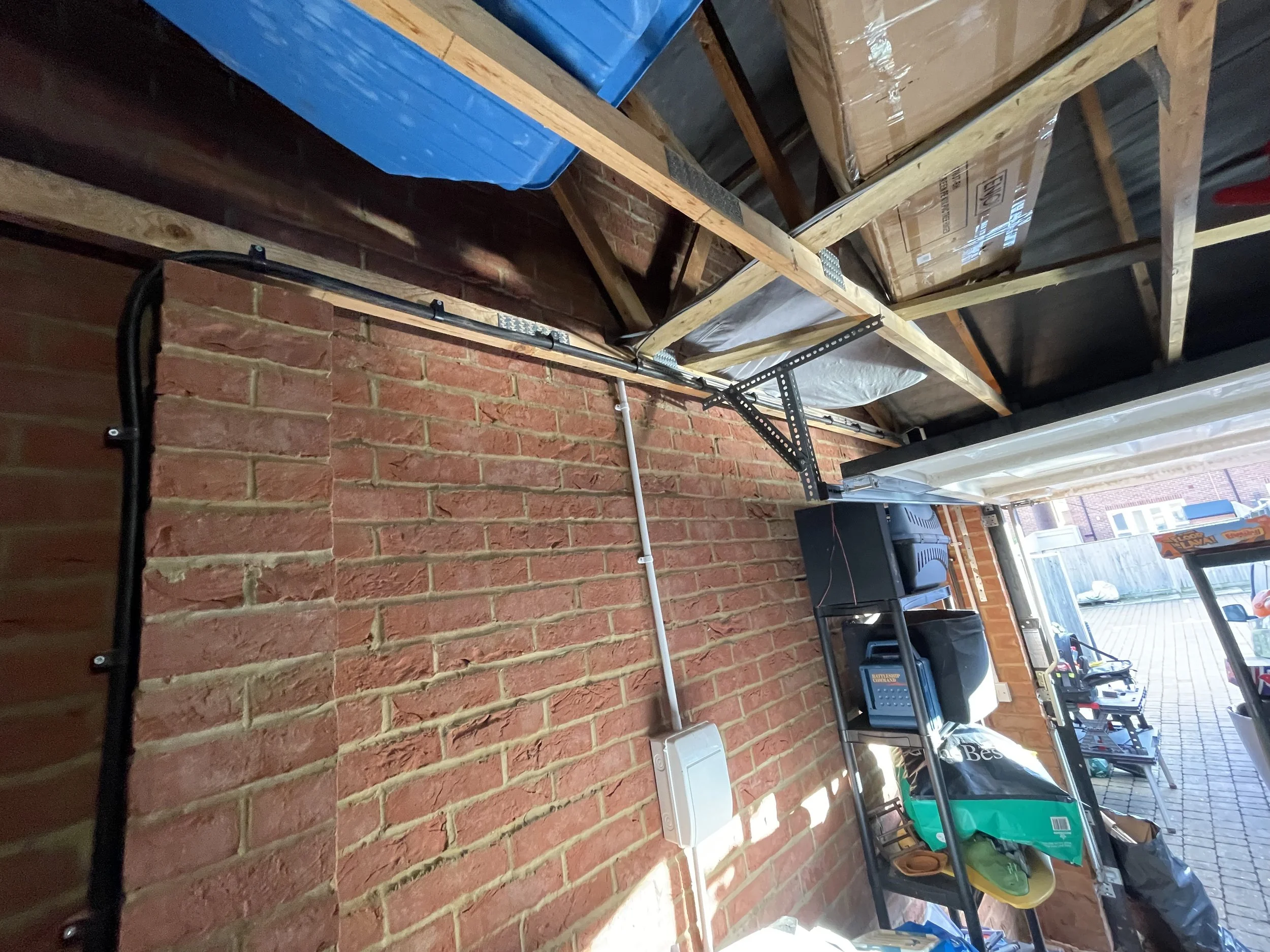 Garage with exposed brick wall, woodworking shelves, and outdoor patio area visible through the open garage door.