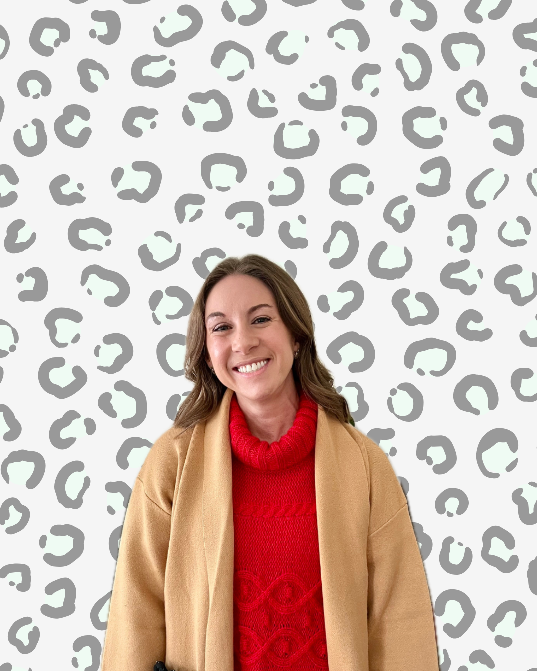 A woman smiling, wearing a red sweater and tan coat, standing in front of a gray and white leopard print background.