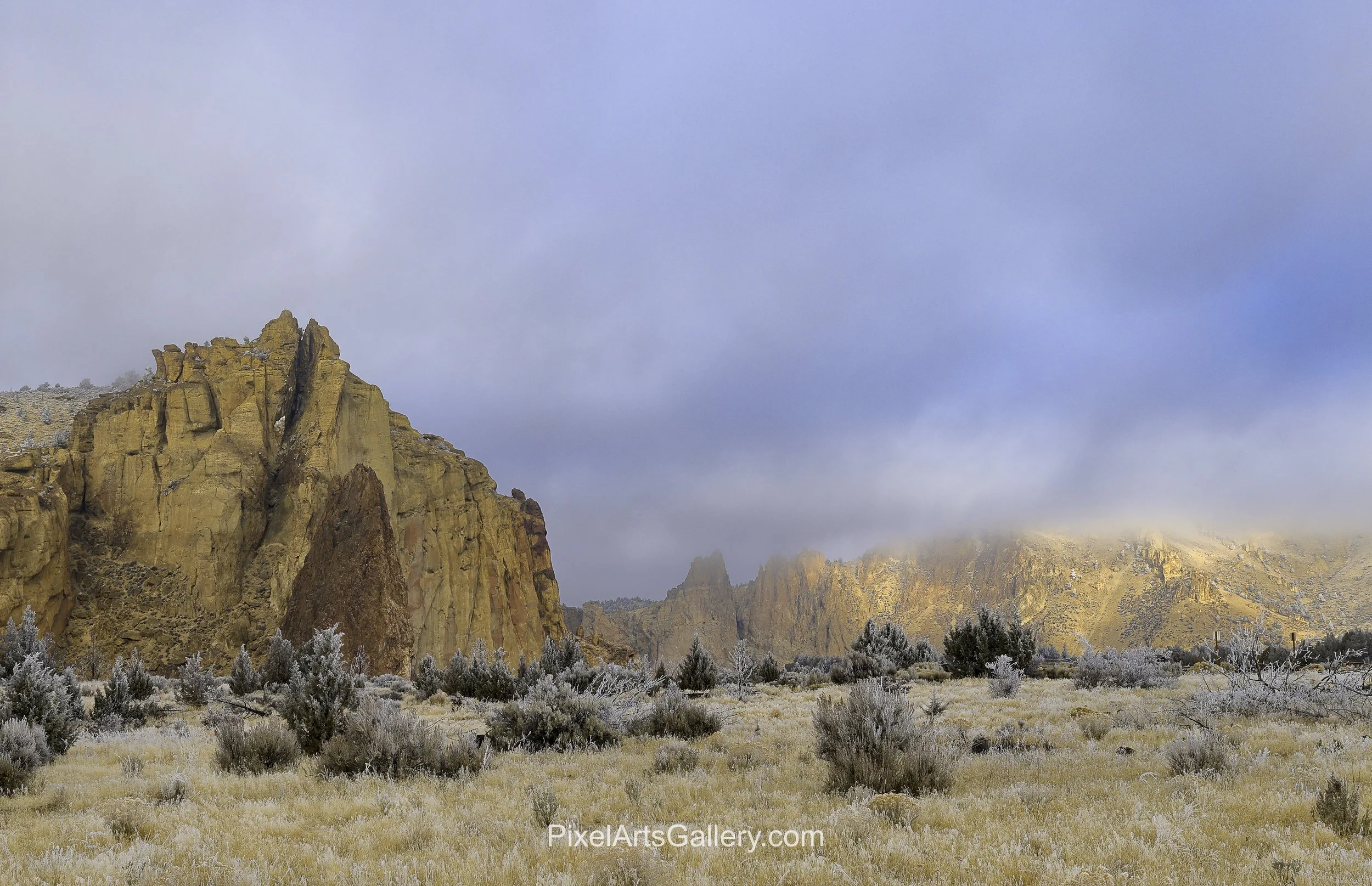 Ethereal Morning at Smith Rock - 

Golden rock formations emerge beneath low, drifting clouds as soft morning light illuminates distant cliffs.