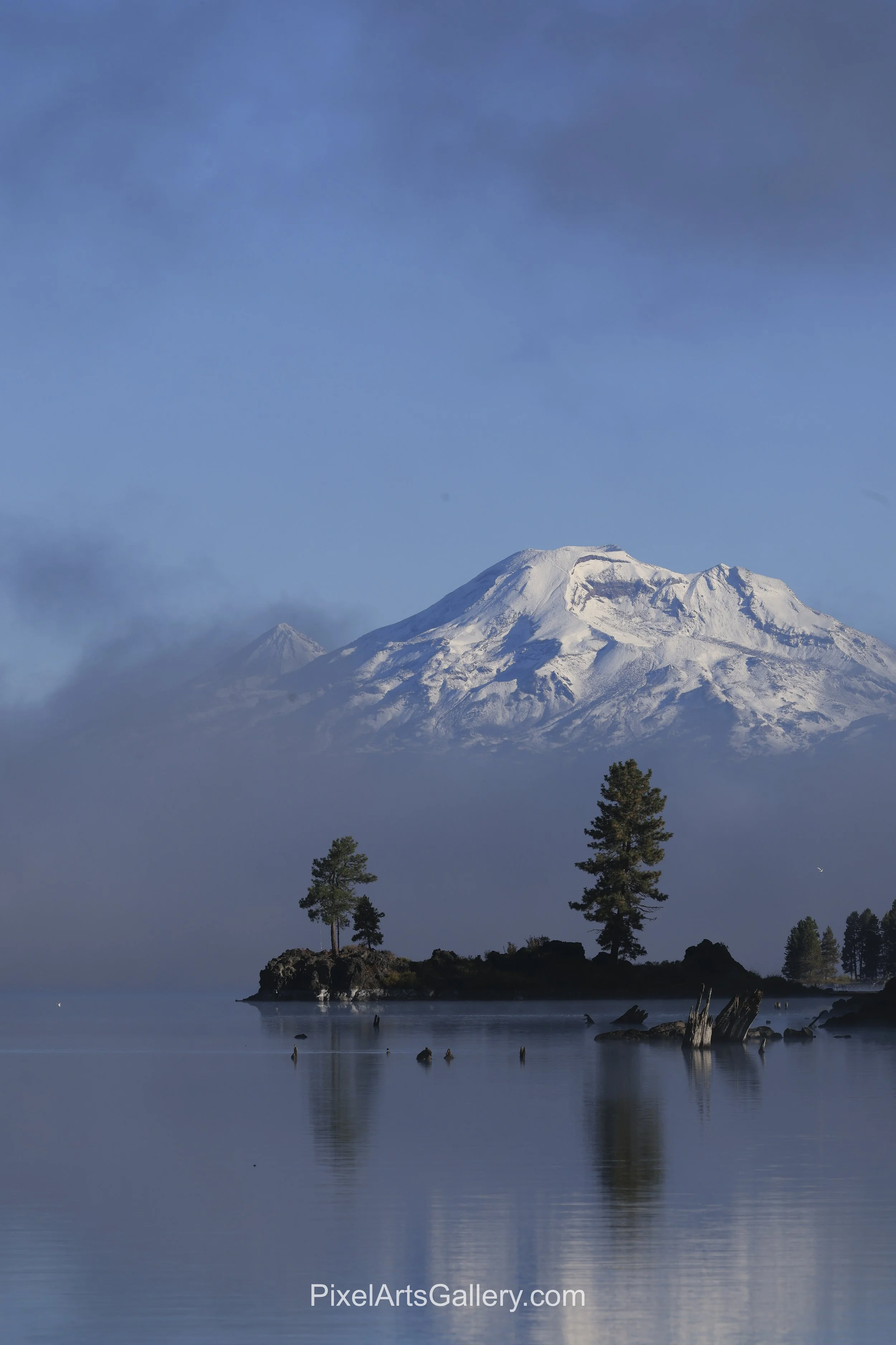 Crane Prairie - 

Snow-covered mountain peak rises above a small pine-covered island in the still waters of Crane Prairie Reservoir.