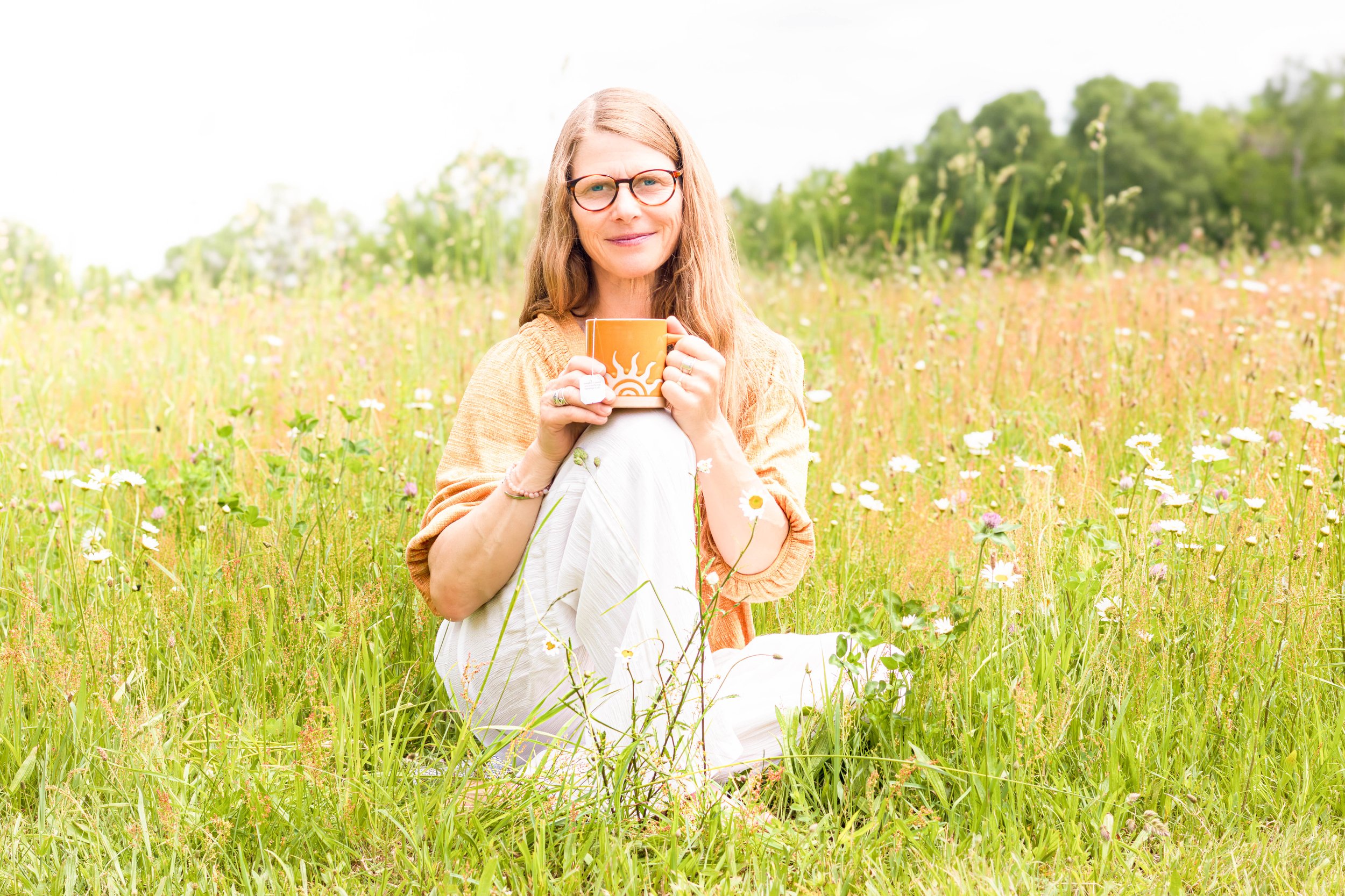 Kristin, founder of Lumina Life & Wellness Coaching, enjoying a peaceful moment in a field of wildflowers.