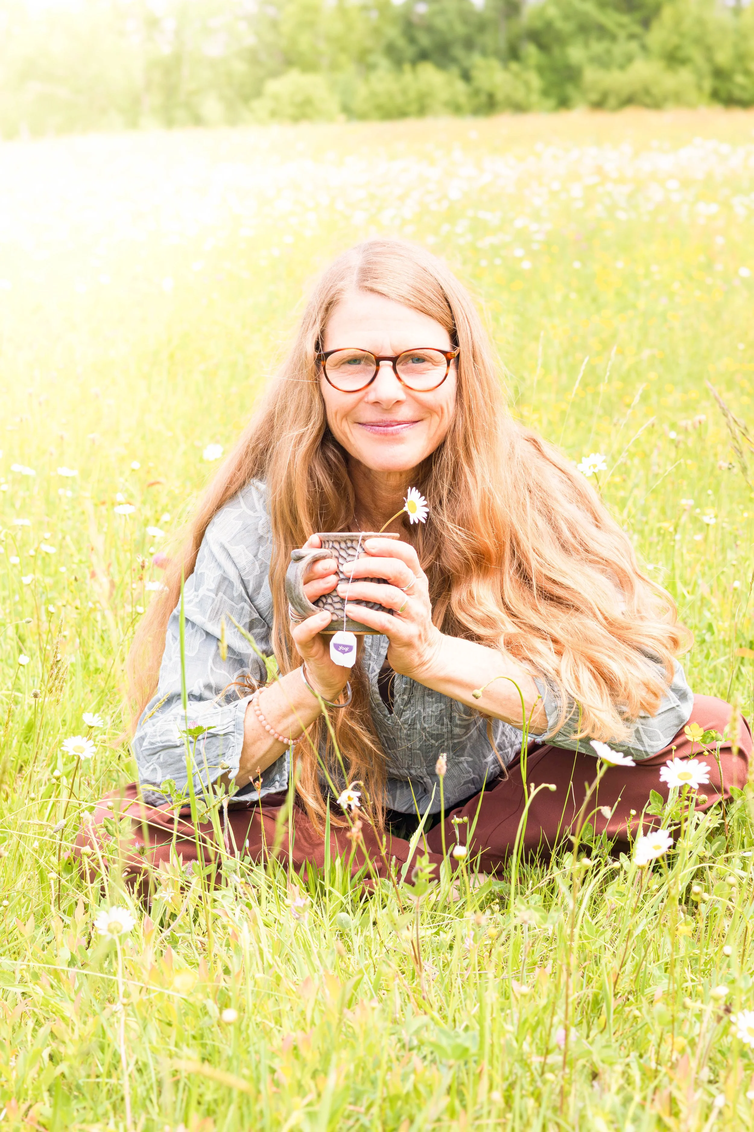 Kristin, founder of Lumina Life & Wellness Coaching, smiling outdoors in a sunny field.