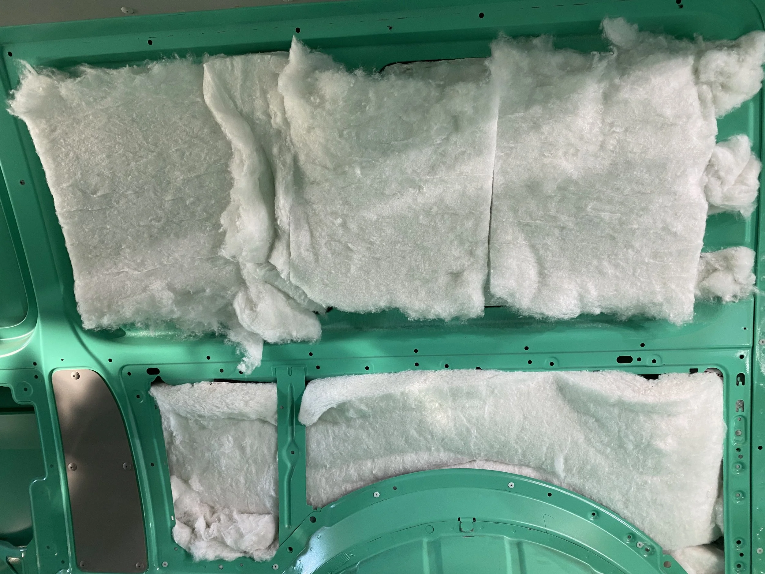 Car door with green frame and white insulation foam panels attached to interior side.