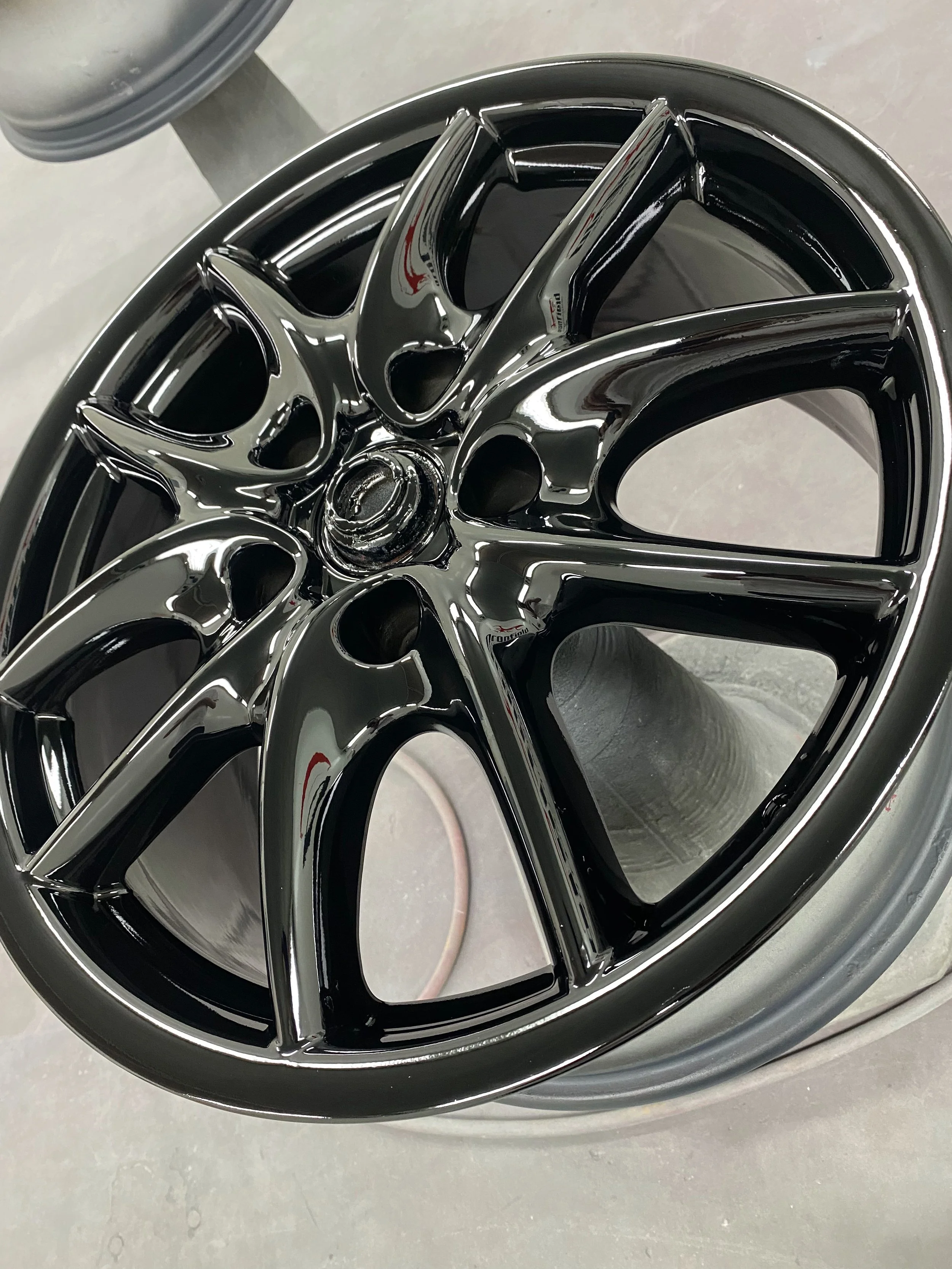 Close-up of a shiny black alloy wheel rim with a metallic finish.
