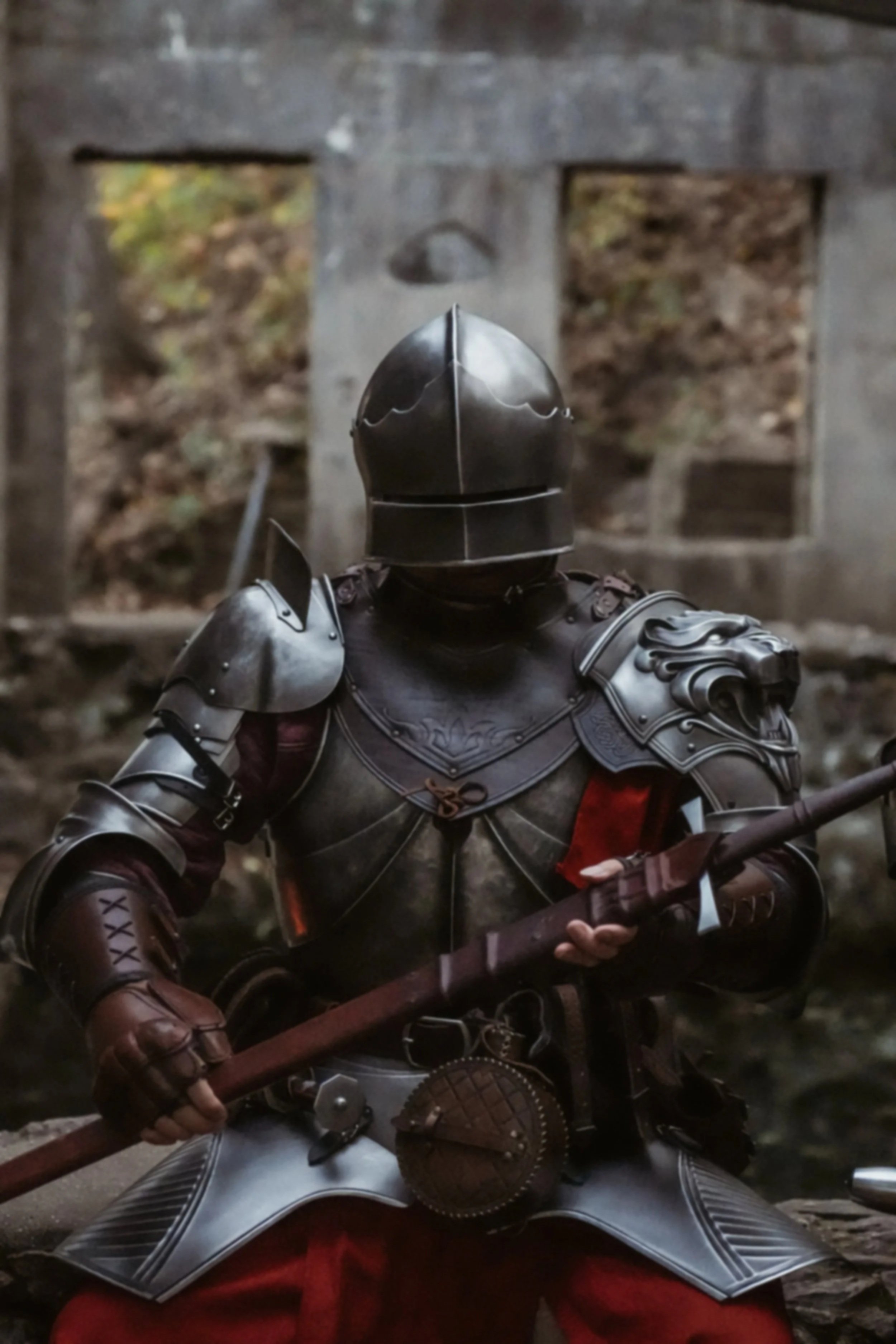 Person dressed in medieval knight armor holding a spear, with a lion emblem on the armor, in front of a stone background.